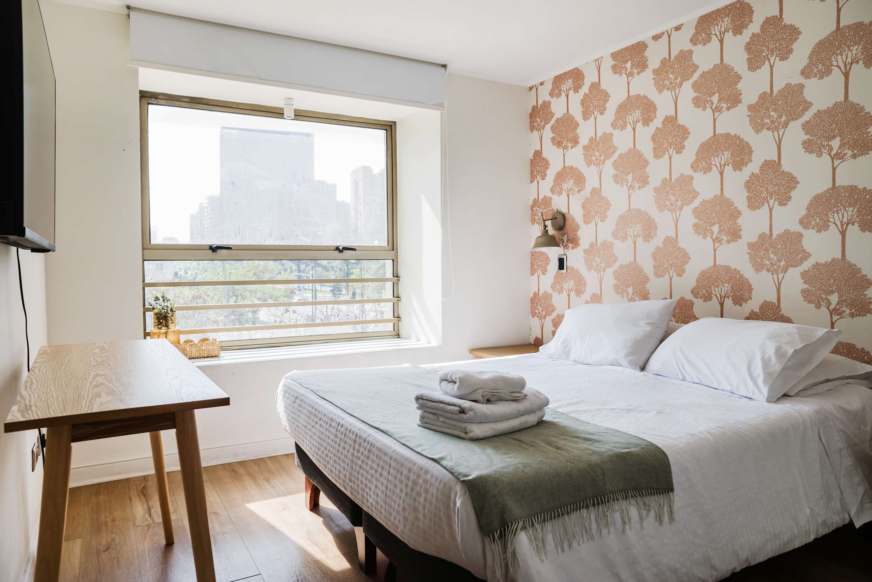 Cozy bedroom with stylish wallpaper and city views, perfect for a relaxing stay.