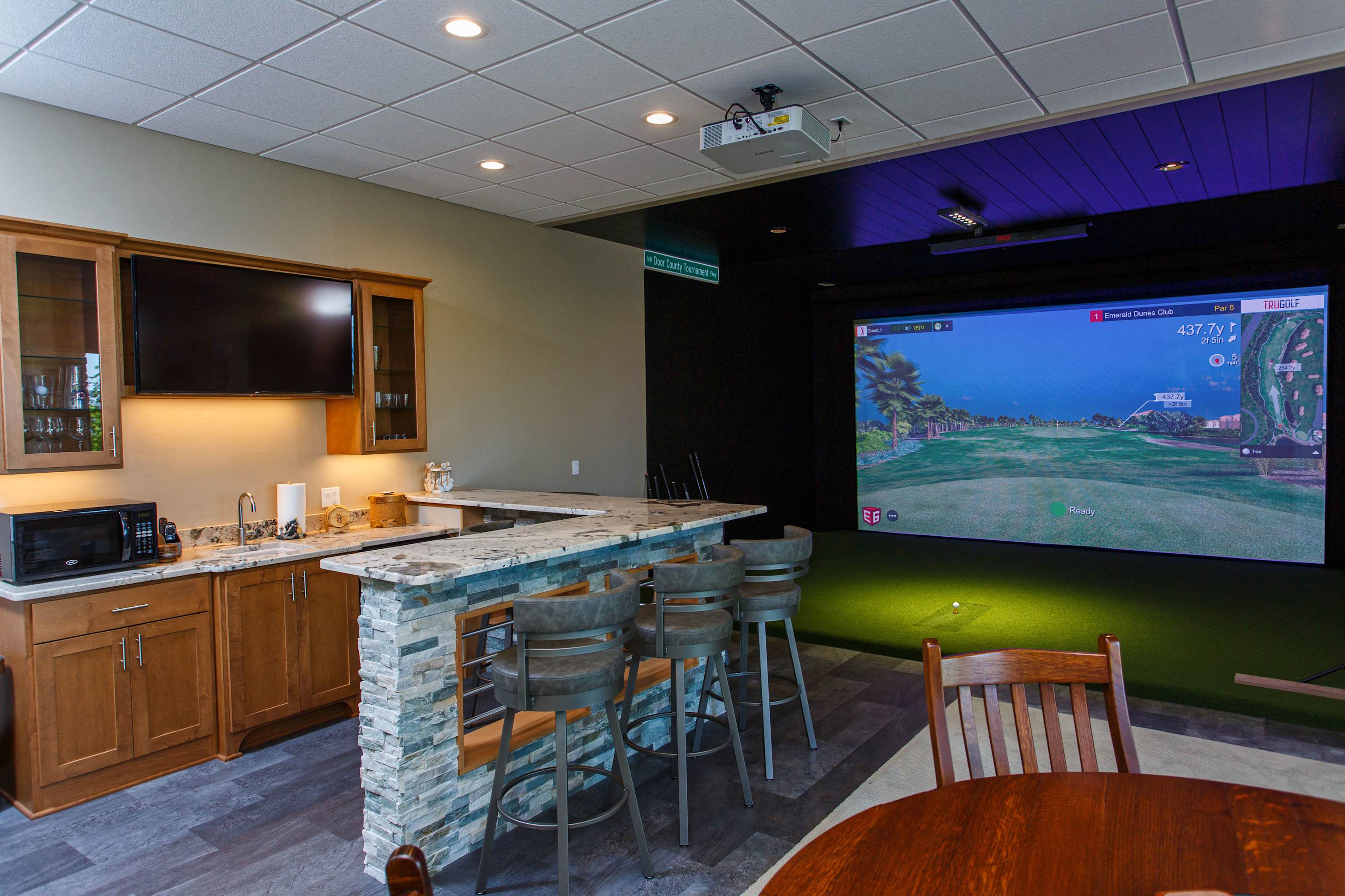 Finished walkout basement is a entertainment center with golf simulator, bar, large screen TV and fireplace.