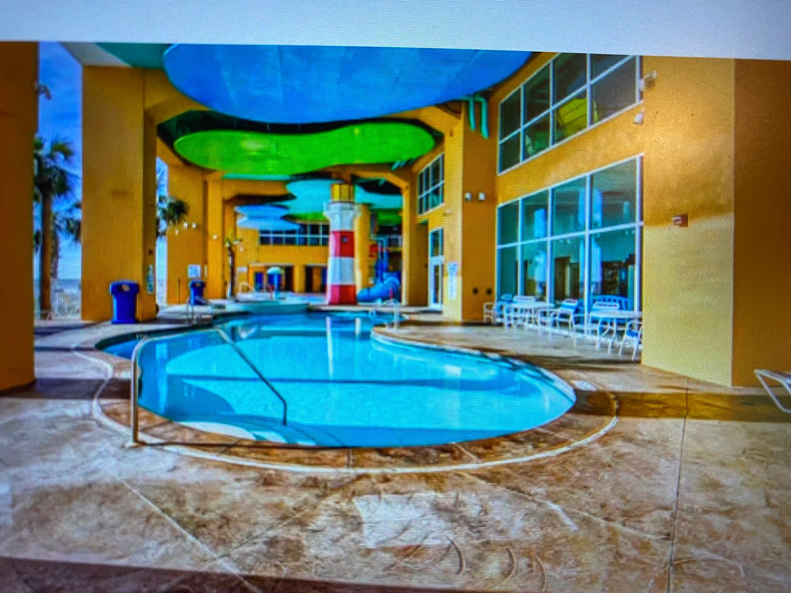 Splash 804E – Pool area with circular pool, lounge chairs, and large windows. Bright blue and green ceiling features.