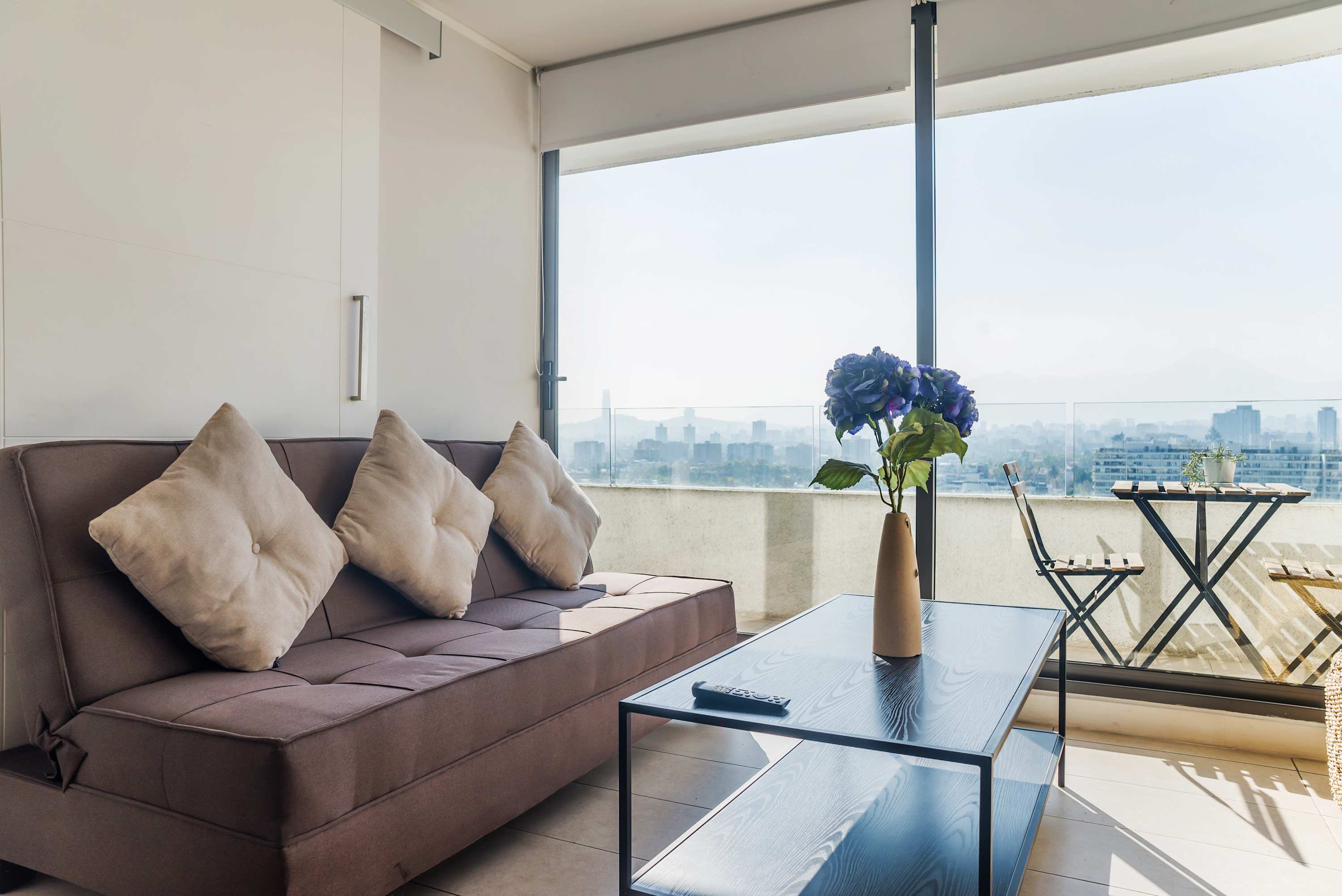 Relax in a stylish living area with stunning city views and a cozy balcony, perfect for morning coffee or evening relaxation.