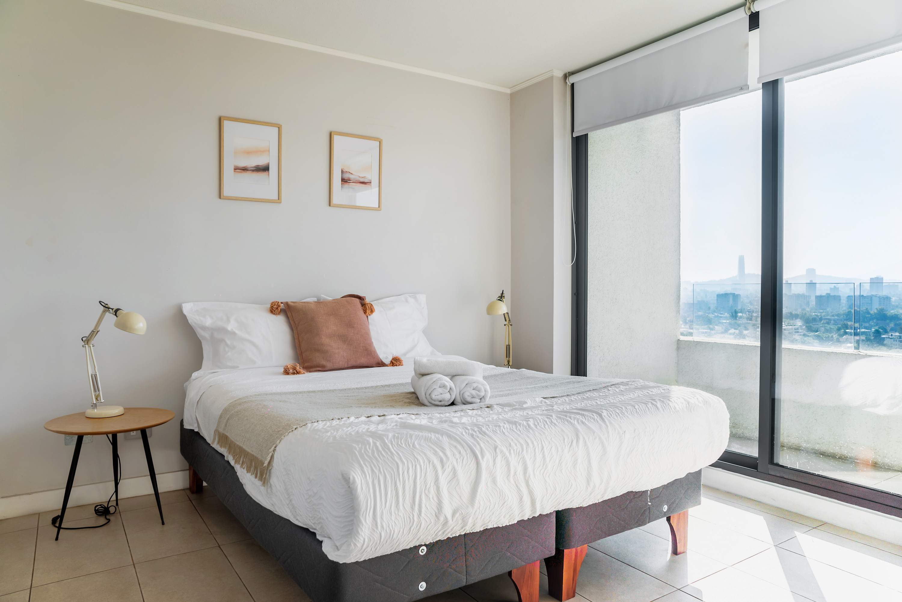 Bright and cozy bedroom with stunning city views, perfect for a relaxing stay.