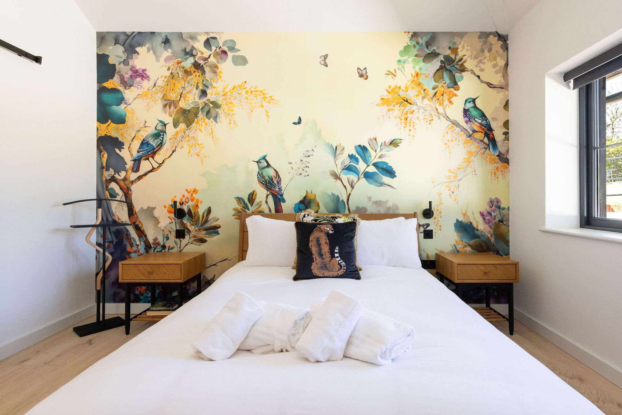Drift into a restful king bedroom with playful wallpaper, soft linens, and peaceful countryside style.