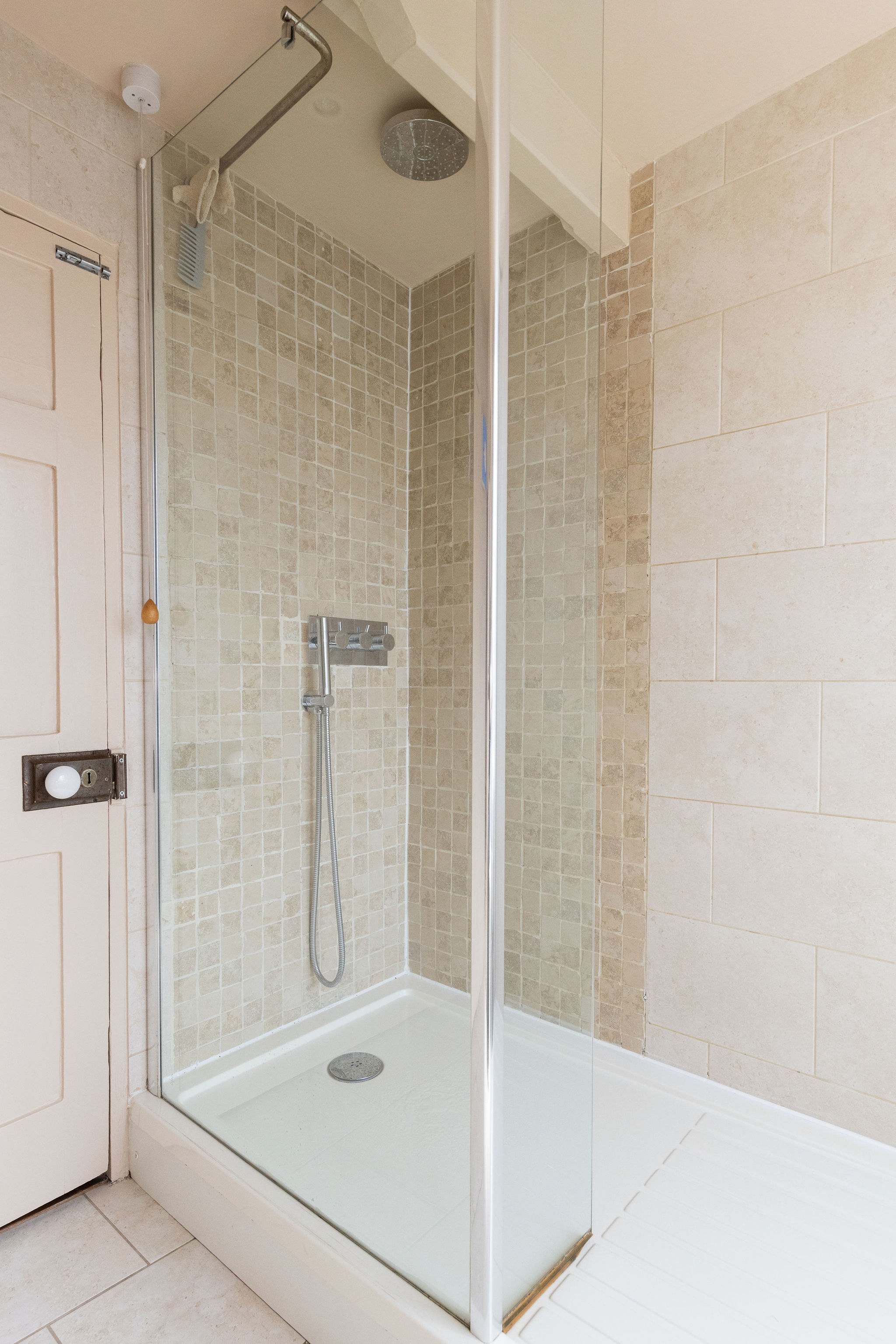Stylish rainfall shower with soft stone tiles and natural light