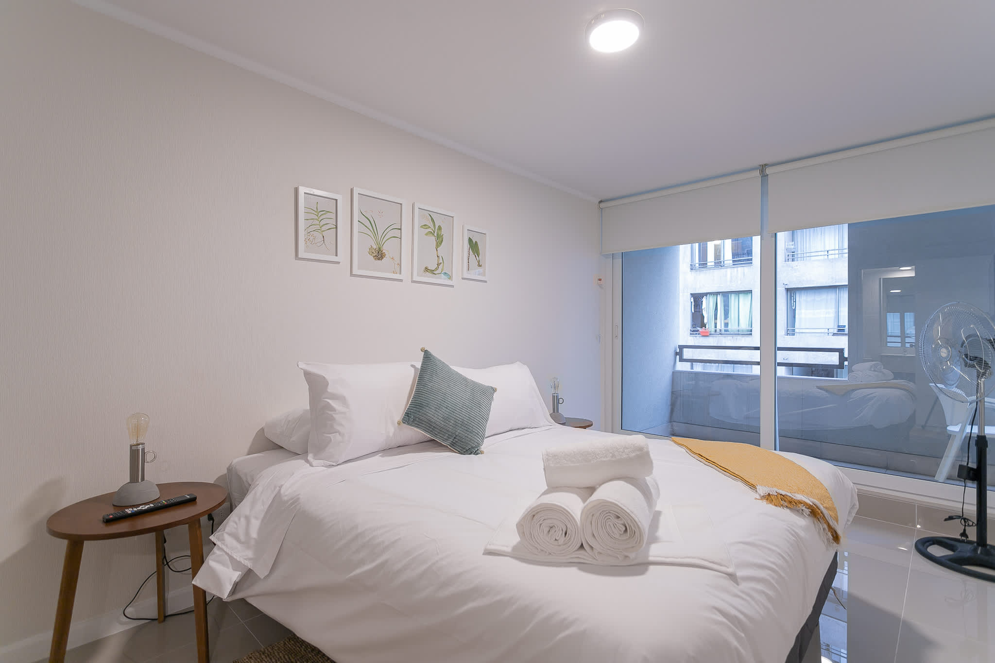 Cozy bedroom with plush bedding and a city view, perfect for a relaxing stay.