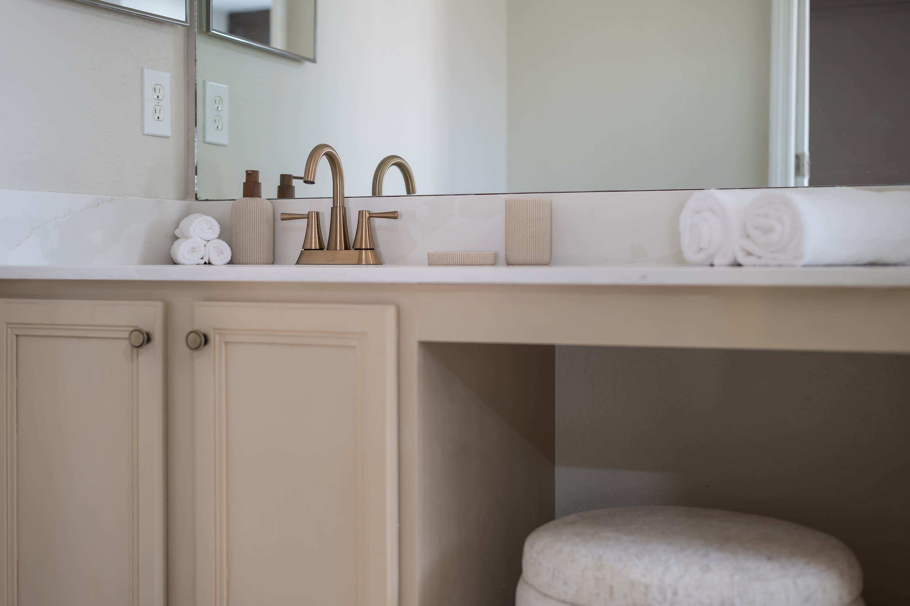 Bathroom setup w/ dual sinks, warm cabinetry & modern lighting