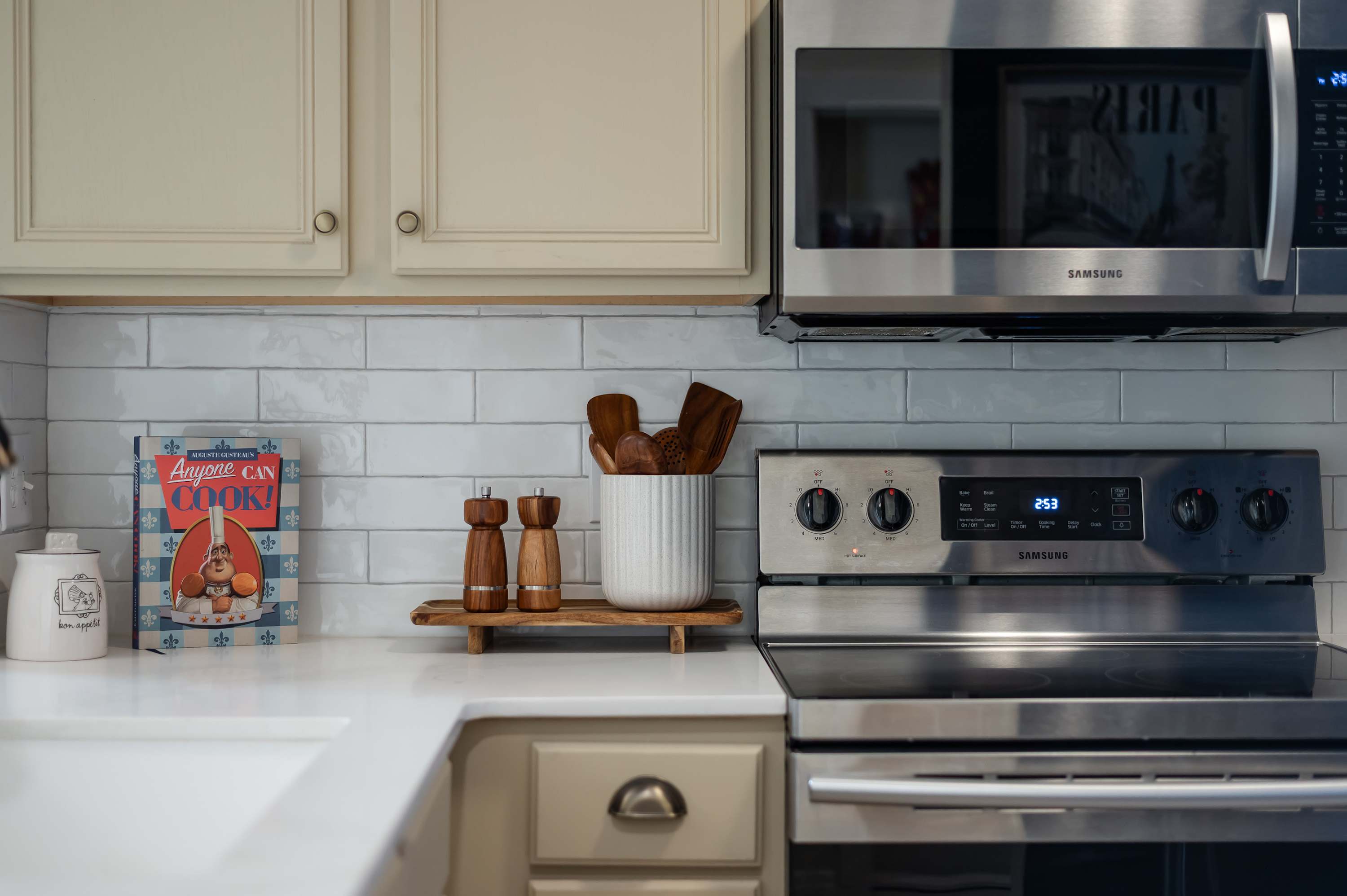 Kitchen corner w/ stainless range, microwave & clean white cabinetry