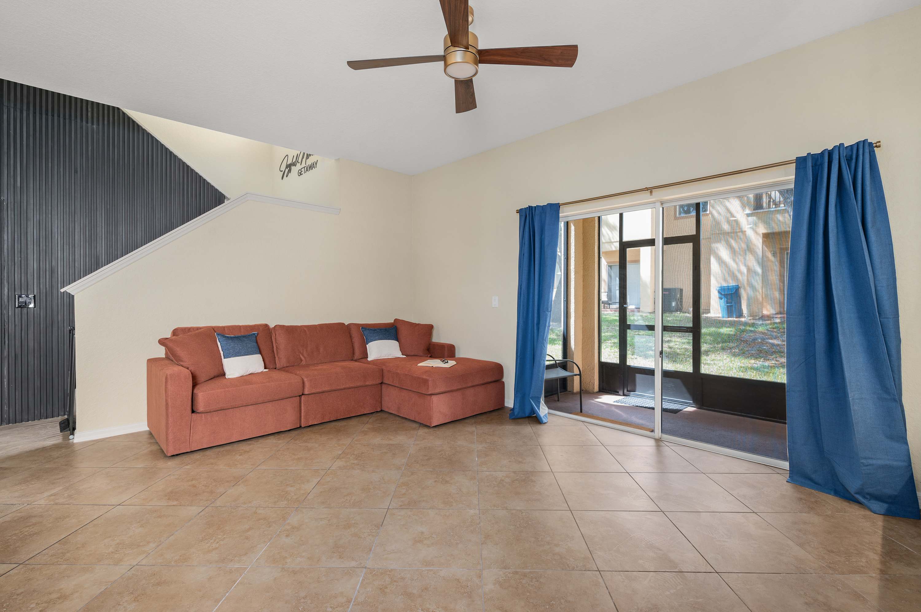 Bright living area w/ cozy sofa, ceiling fan & large doors opening to the patio