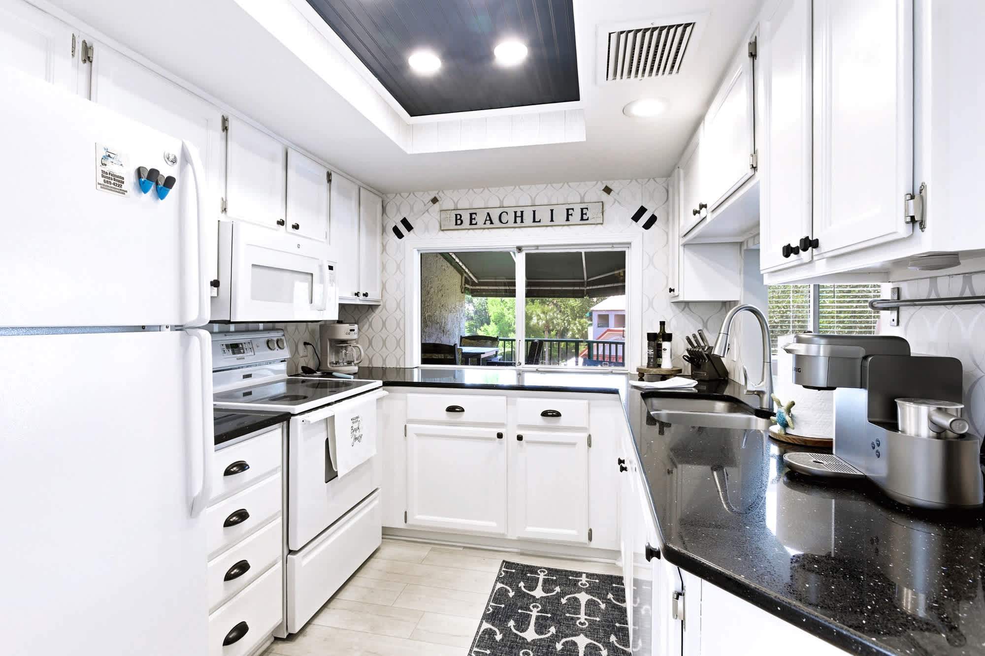 A fully-stocked white kitchen with granite counters, all the cookware you need!