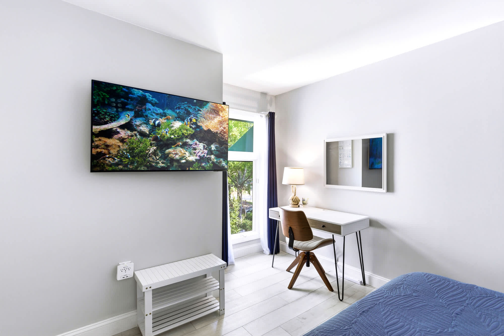 Guest bedroom with a comfy queen bed, mounted TV, and a dedicated workspace for anyone catching up on a few emails.