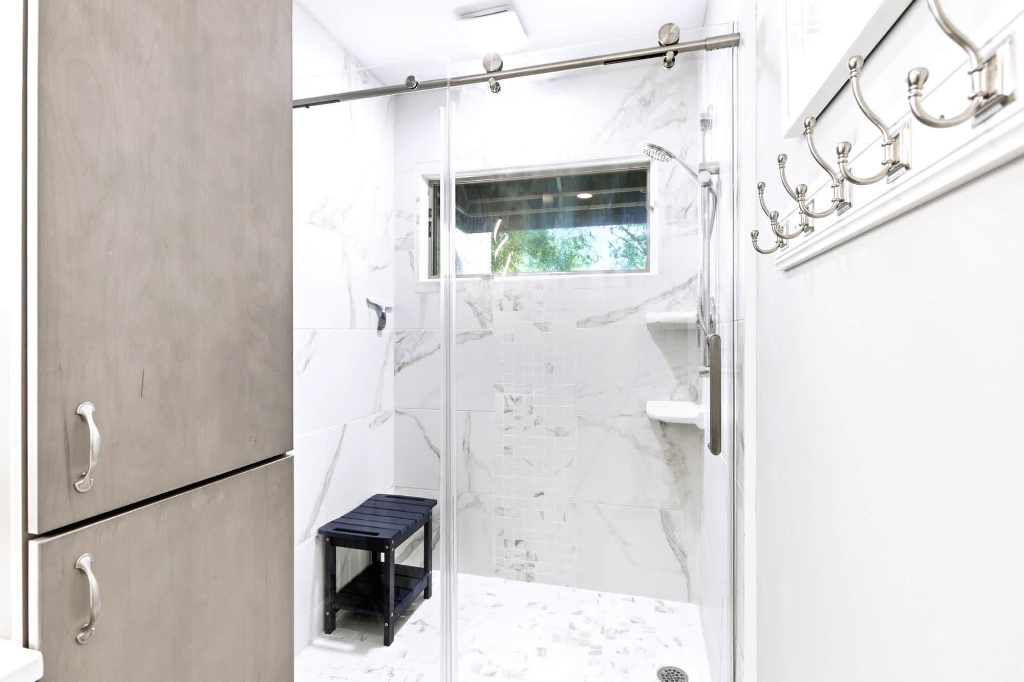 Spa-style en-suite bath with a marble walk-in shower, glass enclosure, and built-in bench - a beautiful place to rinse off after the beach.
