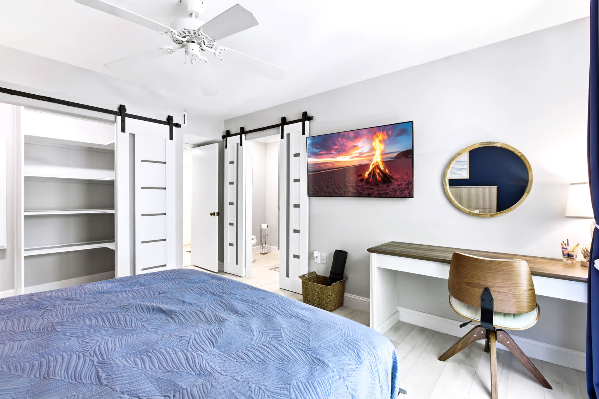 King bed, wall-mounted TV, and roomy barn-door closets make this primary suite as practical as it is stylish, with a sunny window seat for morning coffee.