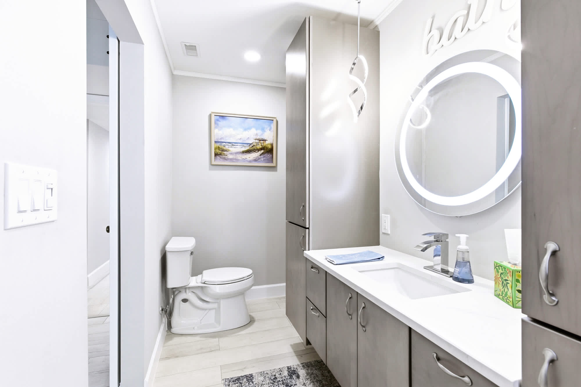 Modern bathroom with a sleek vanity, illuminated round mirror, and ample storage - thoughtfully refreshed throughout.