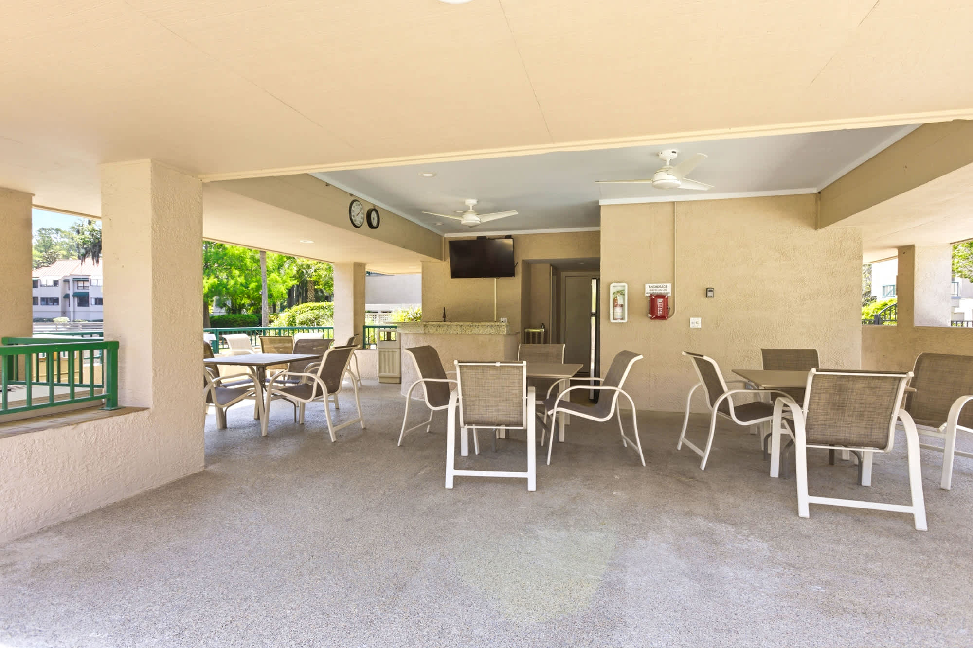 Covered poolside pavilion with seating, ceiling fans, and a TV - a perfect rainy-day backup or a shaded lunch spot.