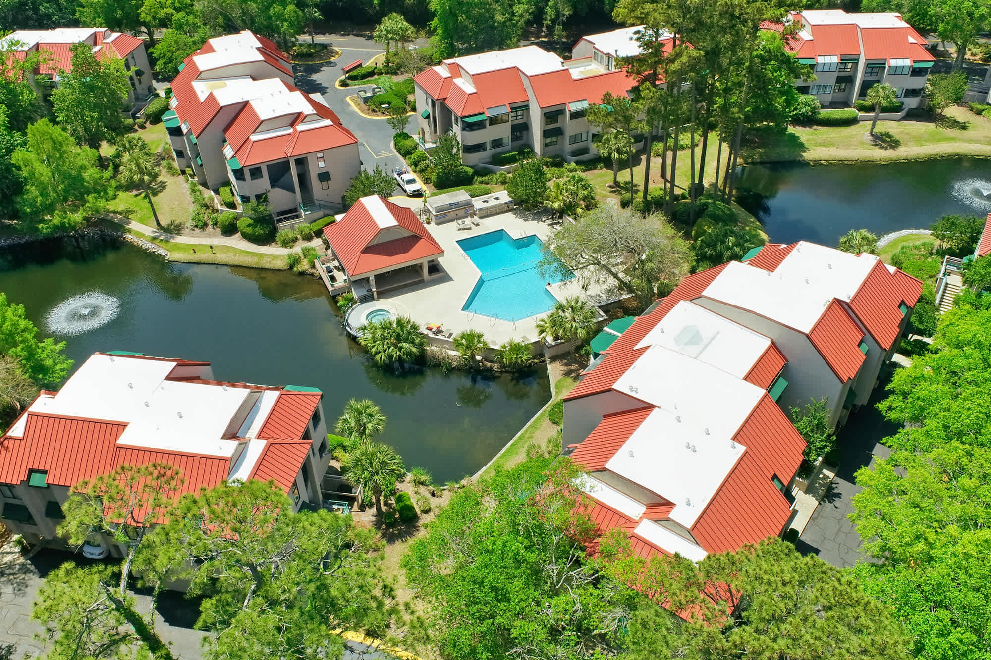 Aerial view of the community: pool, lagoons, and lush canopy all in one frame.