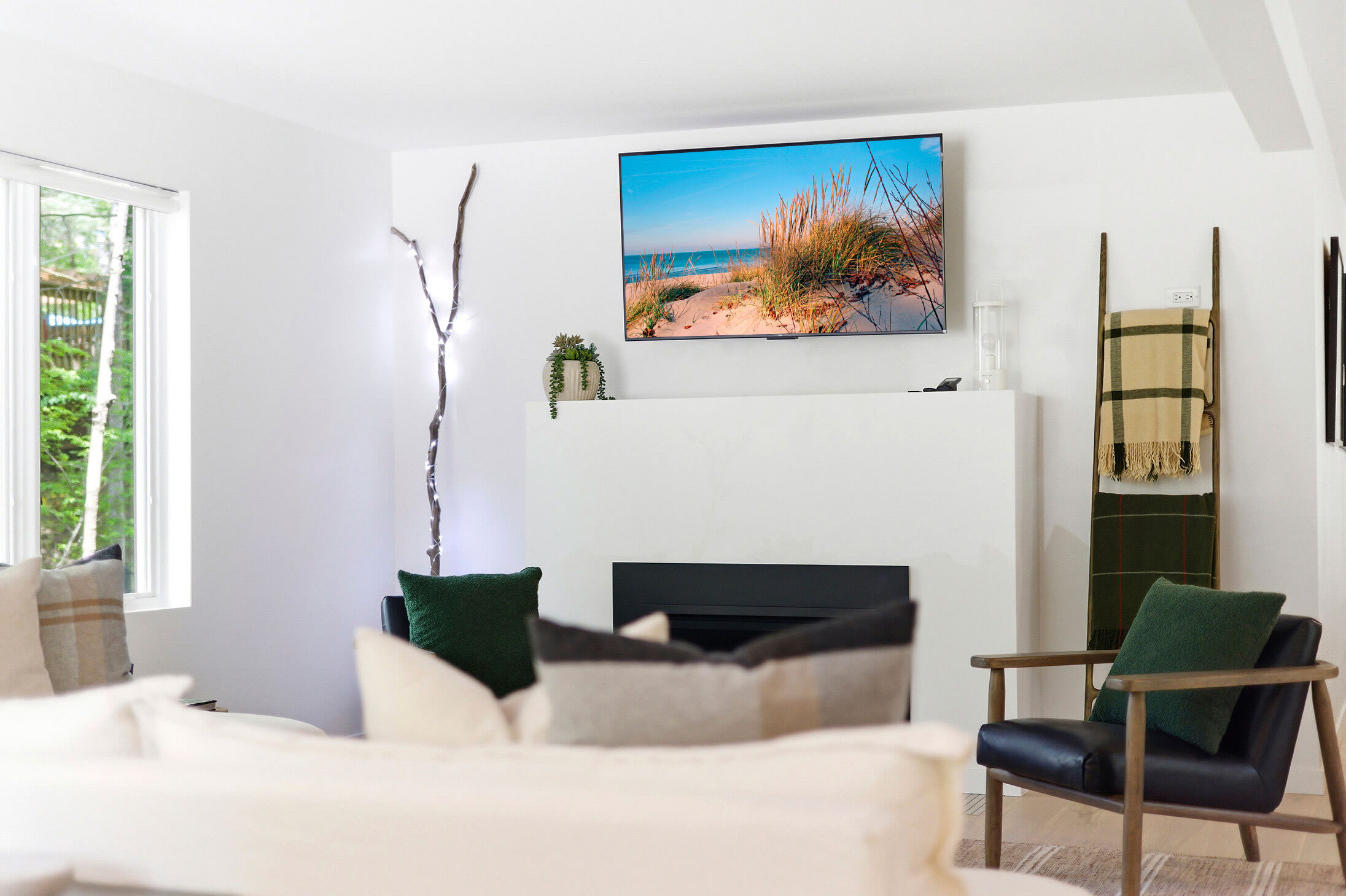 Modern living room with plaster fireplace, forest views, and layered natural textures.