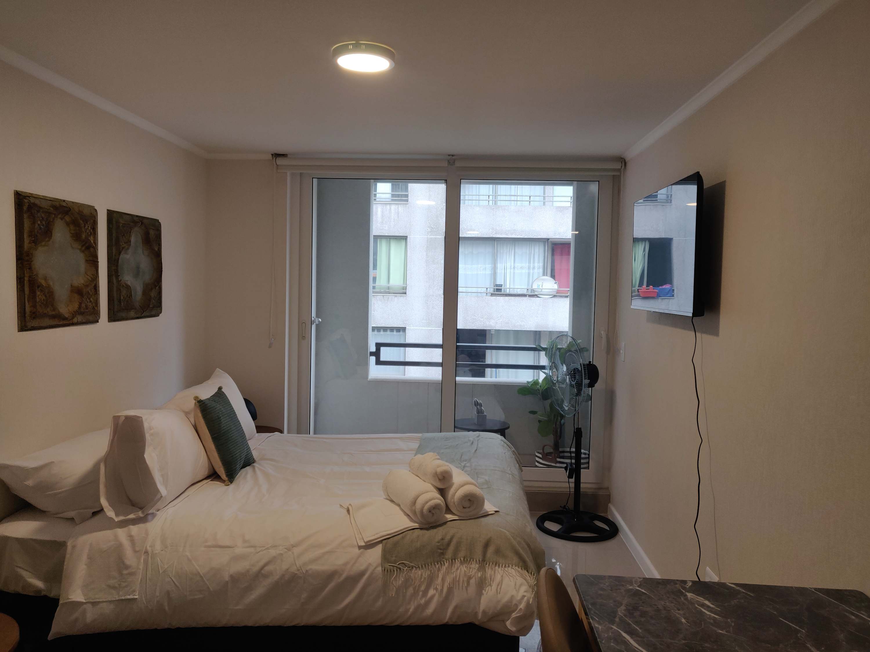 Cozy studio with a comfortable bed, balcony access, and modern amenities for a relaxing stay.