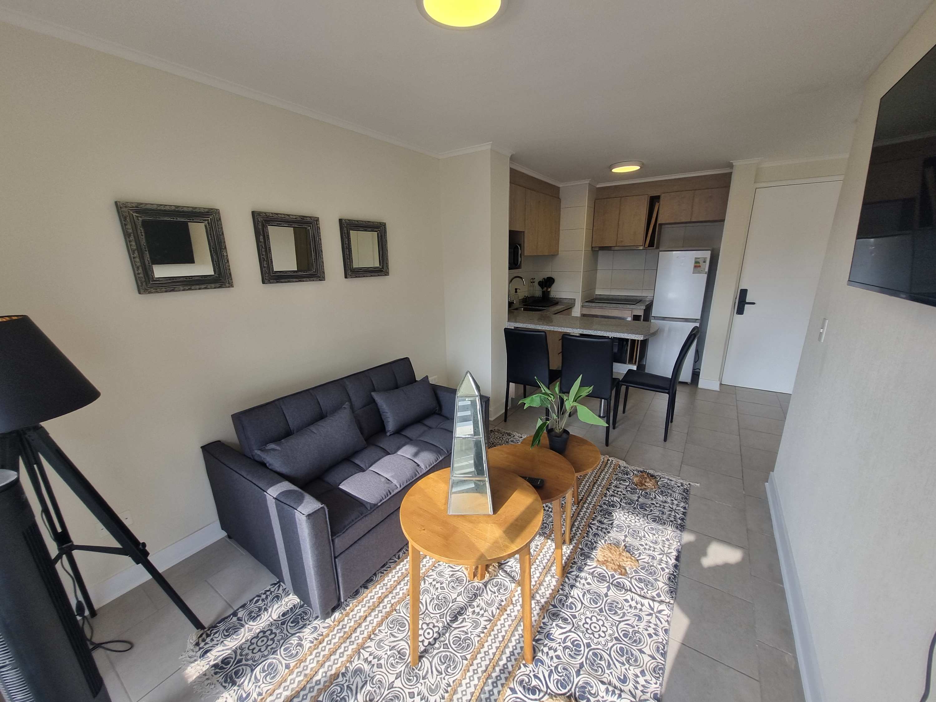 Cozy living area with modern decor and a functional kitchen, perfect for a relaxing stay in the heart of Chile.