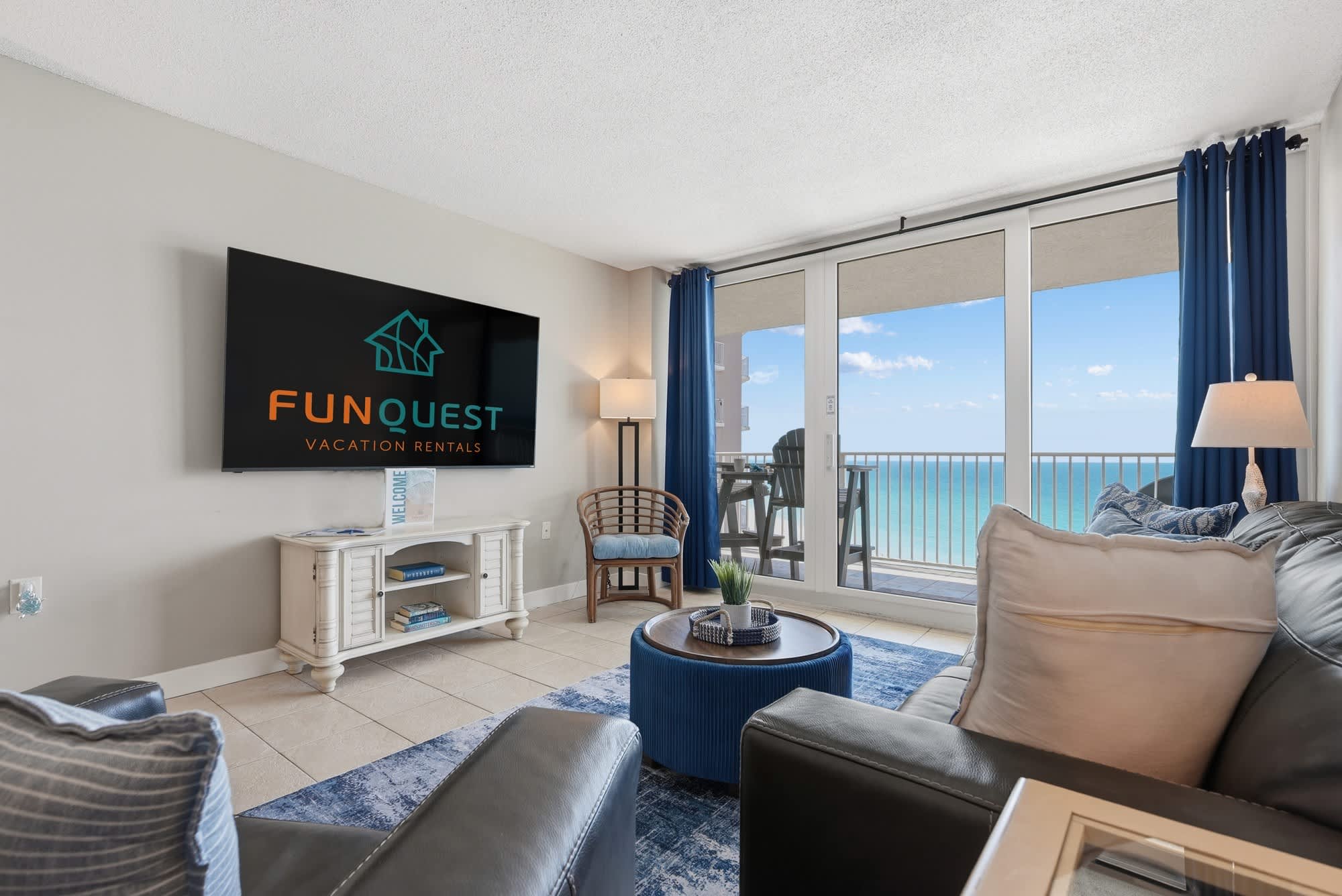 Dunes E1702 – Living room with ocean view, sofa, coffee table, and television.