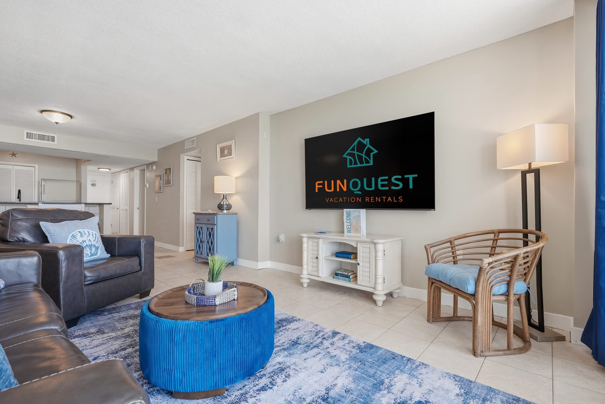Dunes E1702 – Cozy living room with sofa, coffee table, TV, and blue decor elements.
