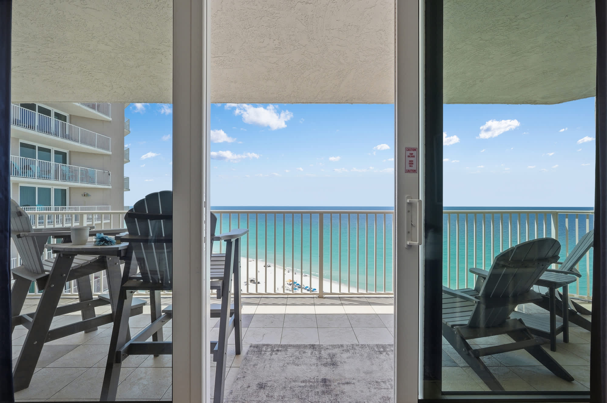 Dunes E1702 – Balcony view with two chairs overlooking the beach and ocean.
