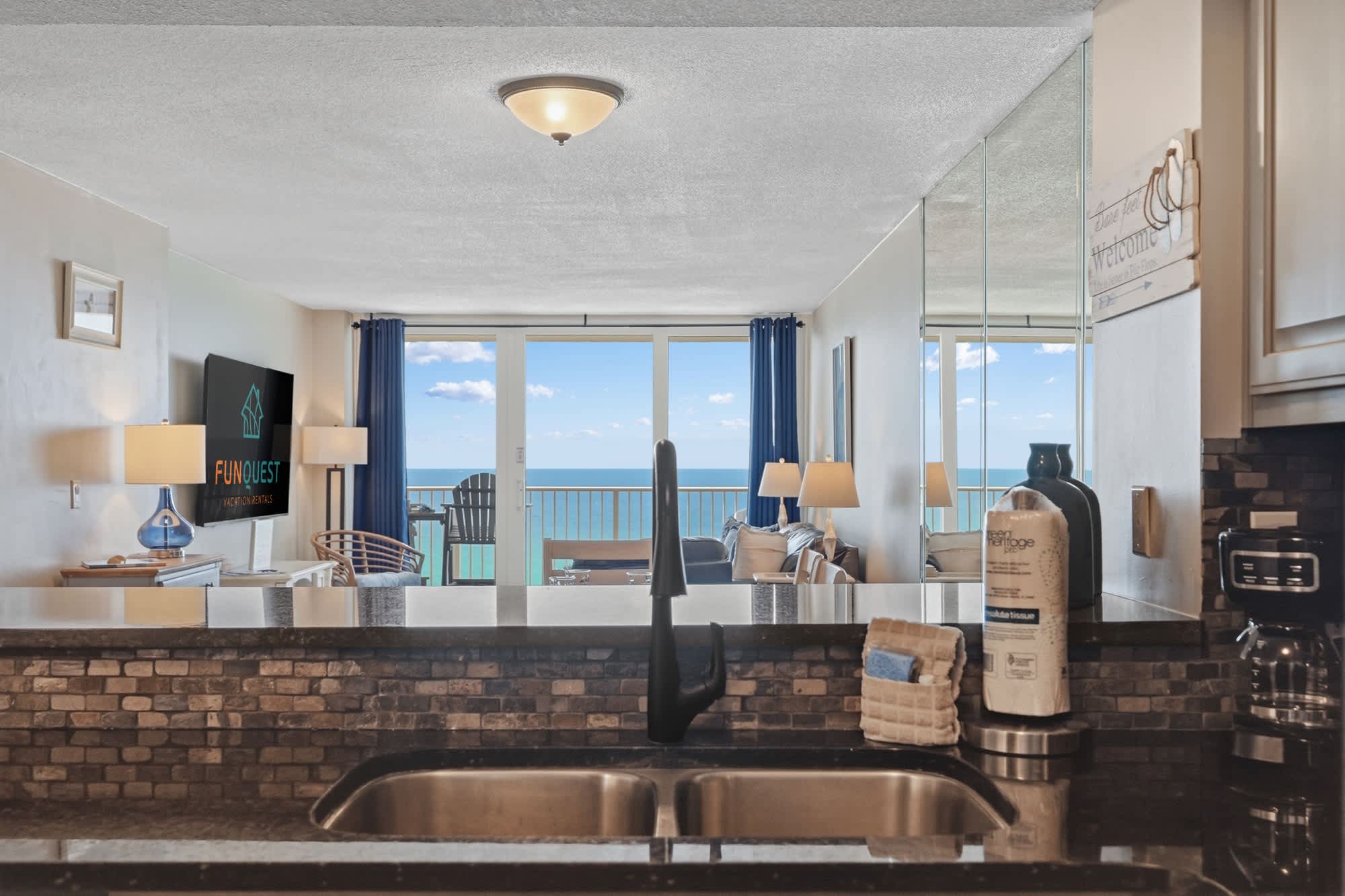 Dunes E1702 – Living room with ocean view, kitchen bar, and modern decor.