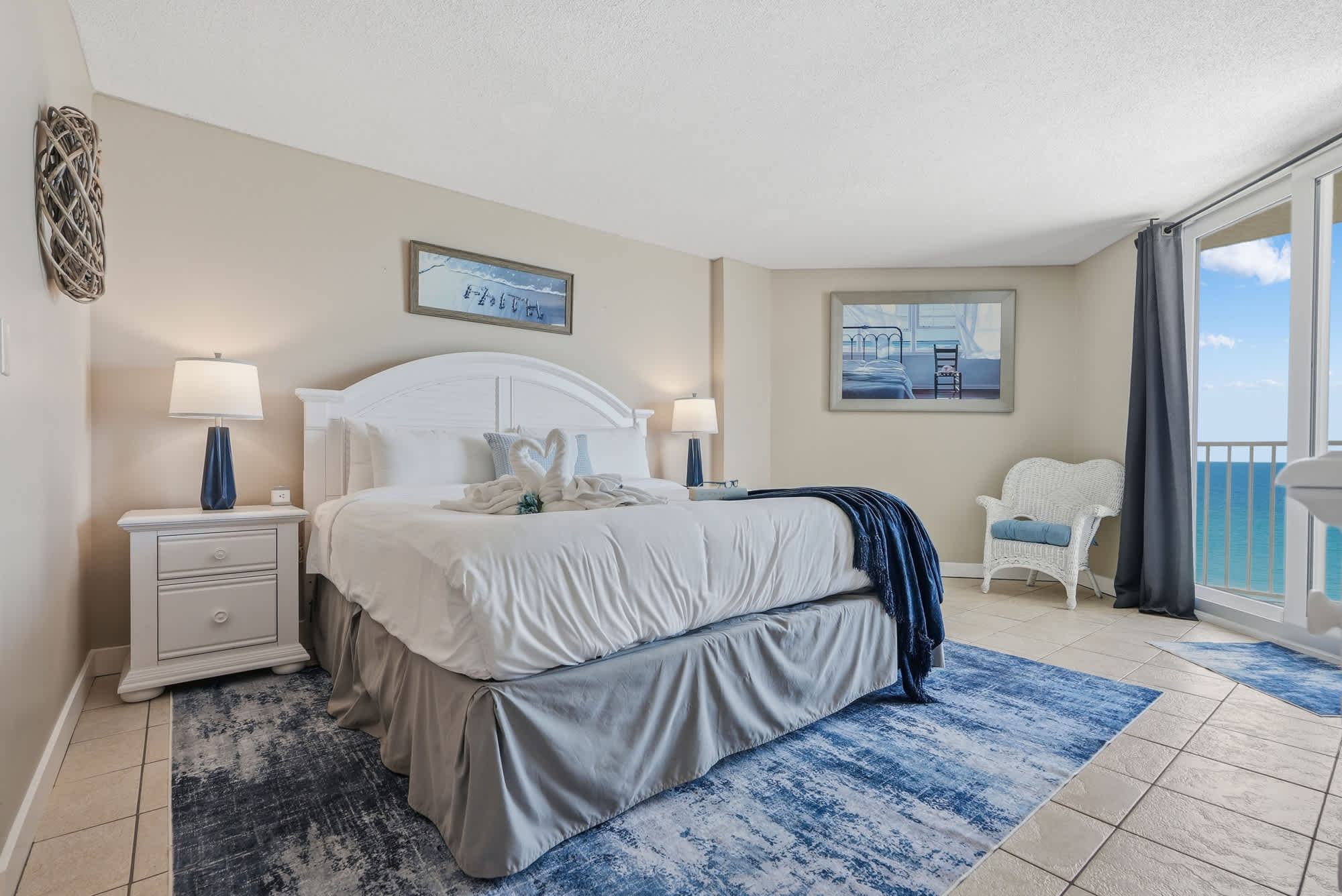 Dunes E1702 – Bright bedroom with a large bed, ocean view, and light-colored furnishings.