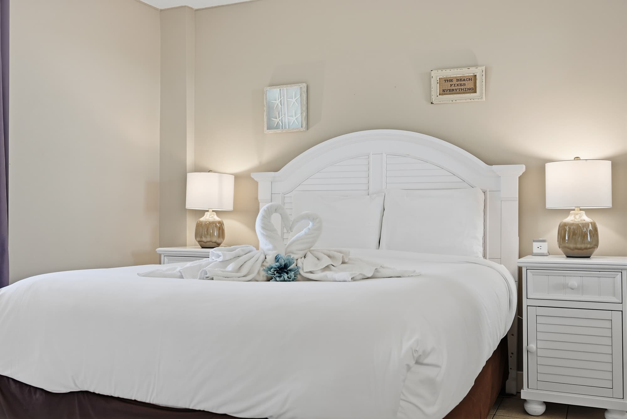 Dunes E1702 – Cozy bedroom with a large bed, decorative swan towels, and bedside lamps.