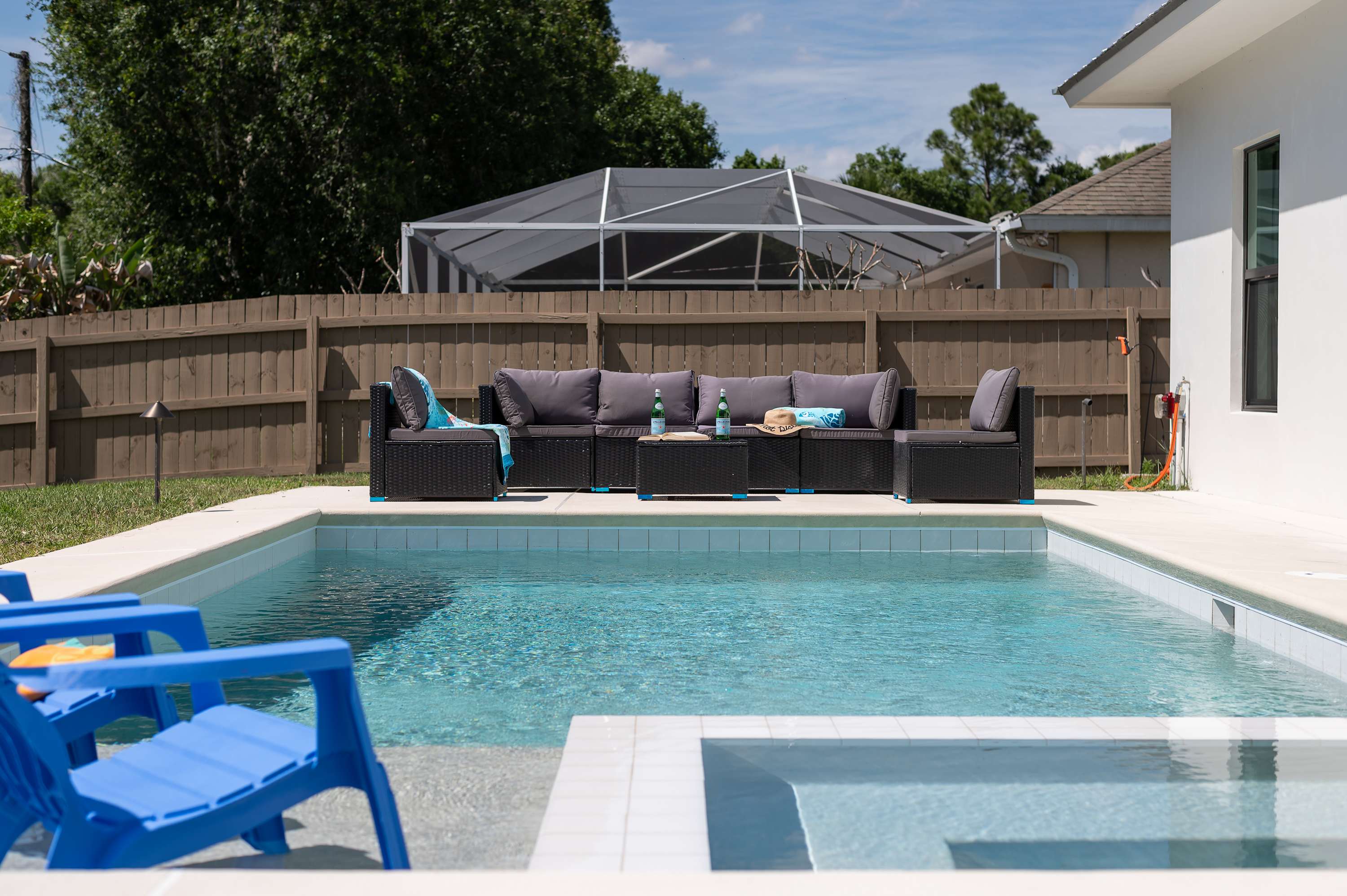Outdoor pool area with cushioned seating and blue lounge chairs for relaxing.
