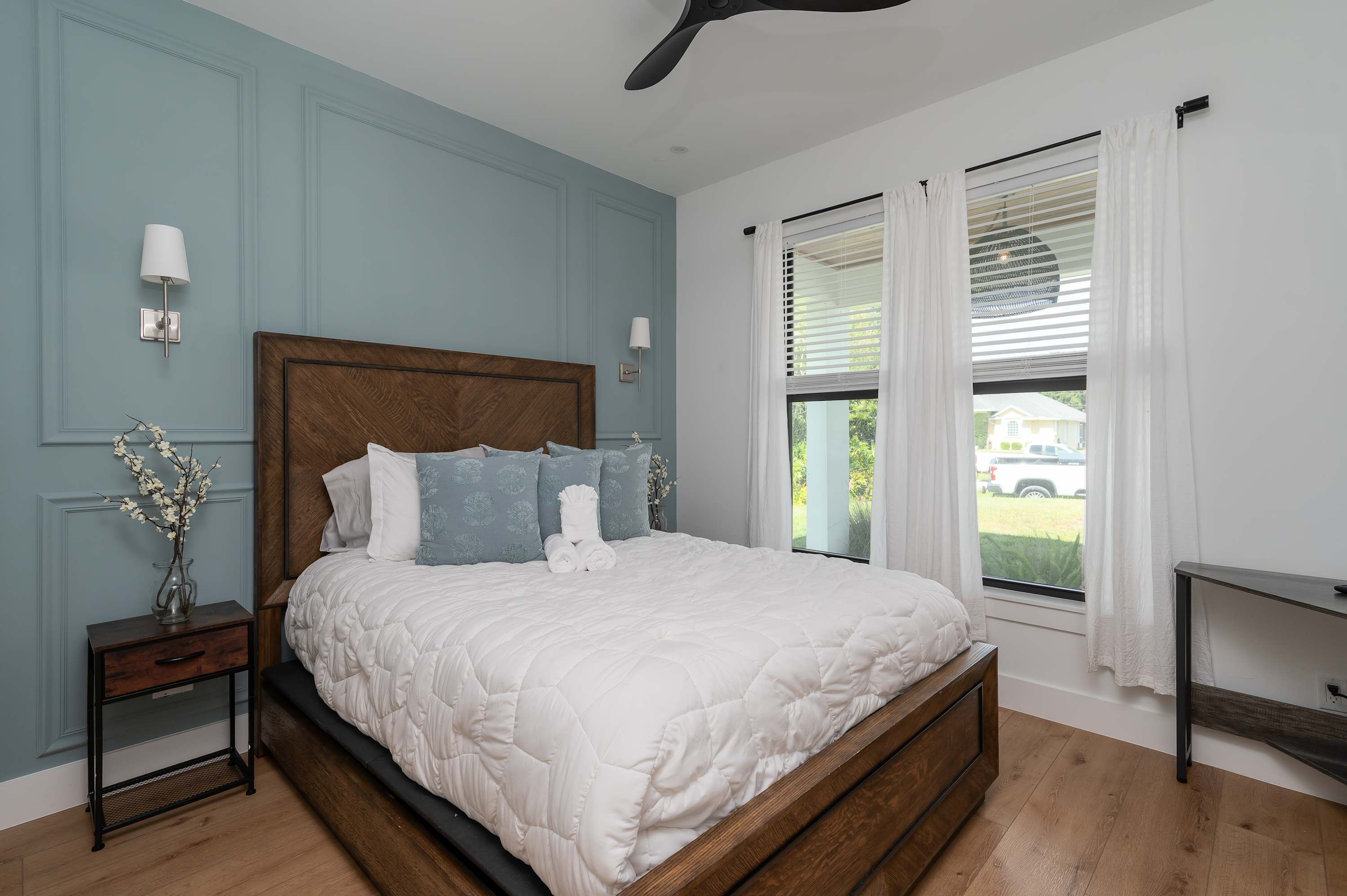 Relax in this modern bedroom featuring a wooden bed frame and soft blue accent wall.