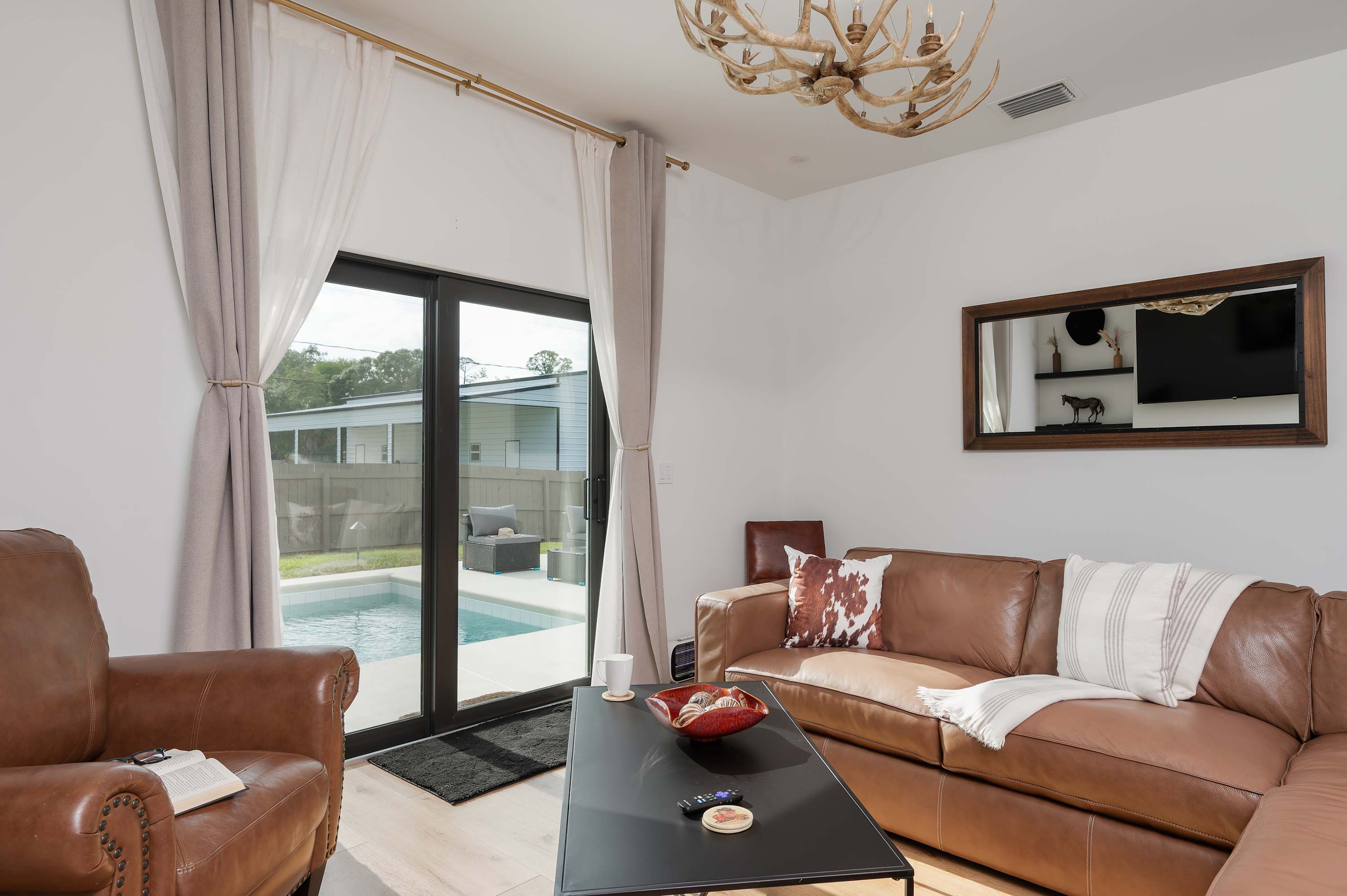 Relax in the cozy living room with leather seating and pool access through sliding glass doors.