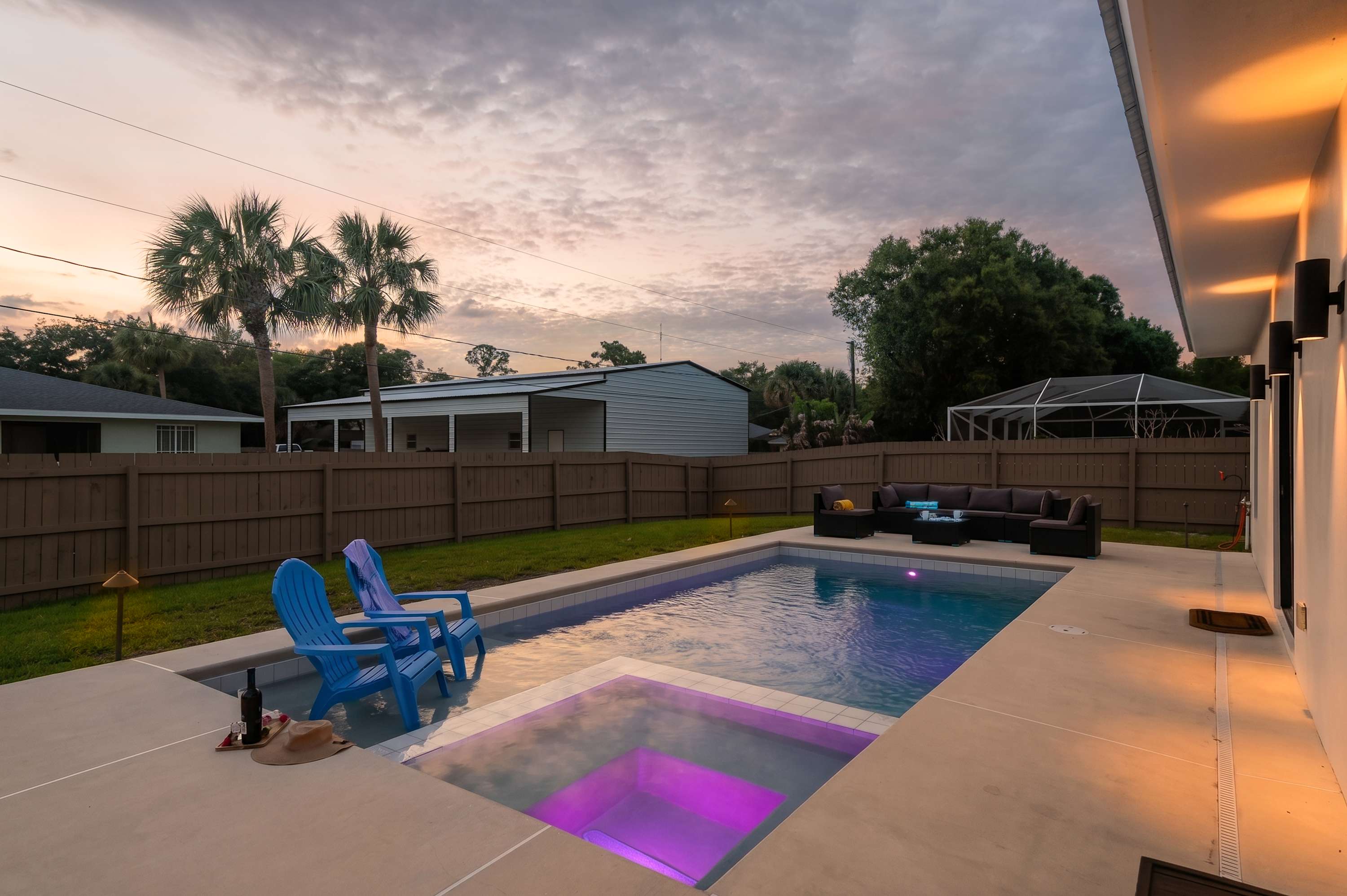 Relax by the modern pool and illuminated spa at sunset in this private backyard.