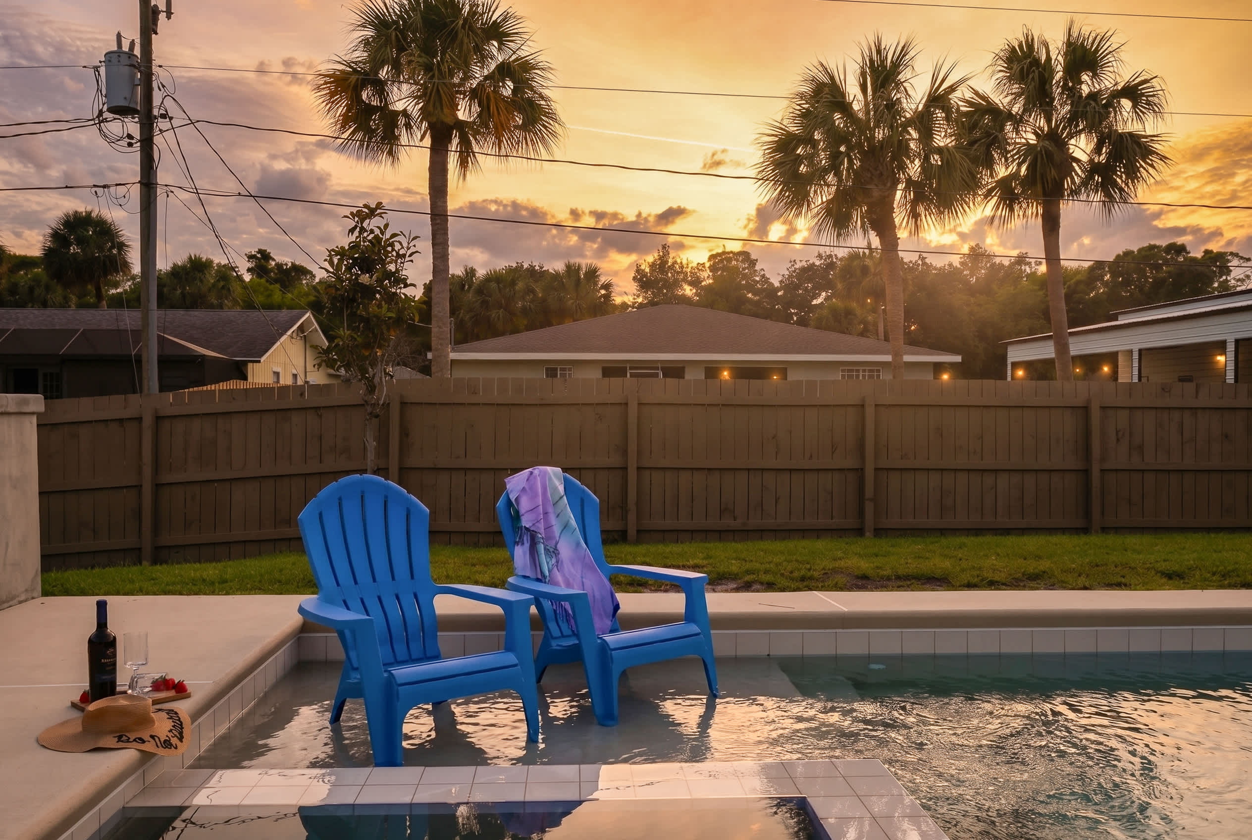 Relax by the pool in comfortable blue chairs during a peaceful sunset.