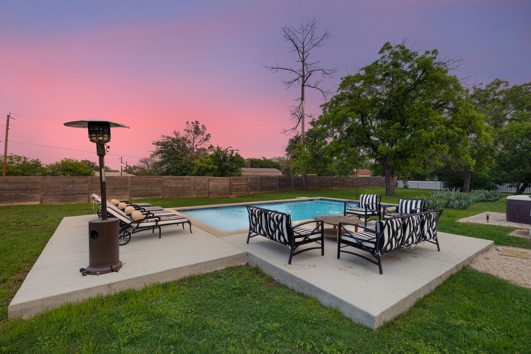 Escape to our outdoor sanctuary with a hot tub, grill, and private yard view, perfect for dining and relaxation.