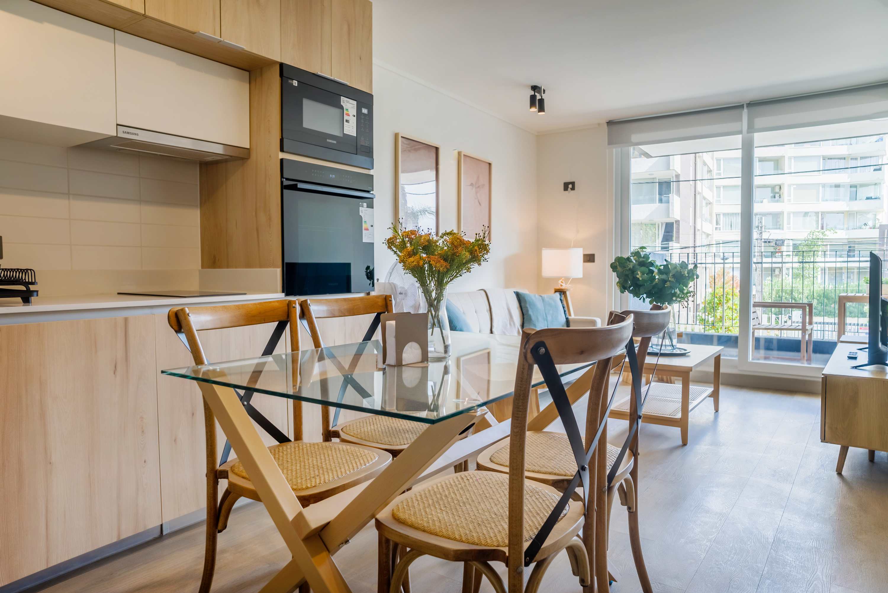 Bright and modern living area with a cozy sofa, dining space, and large windows offering plenty of natural light.