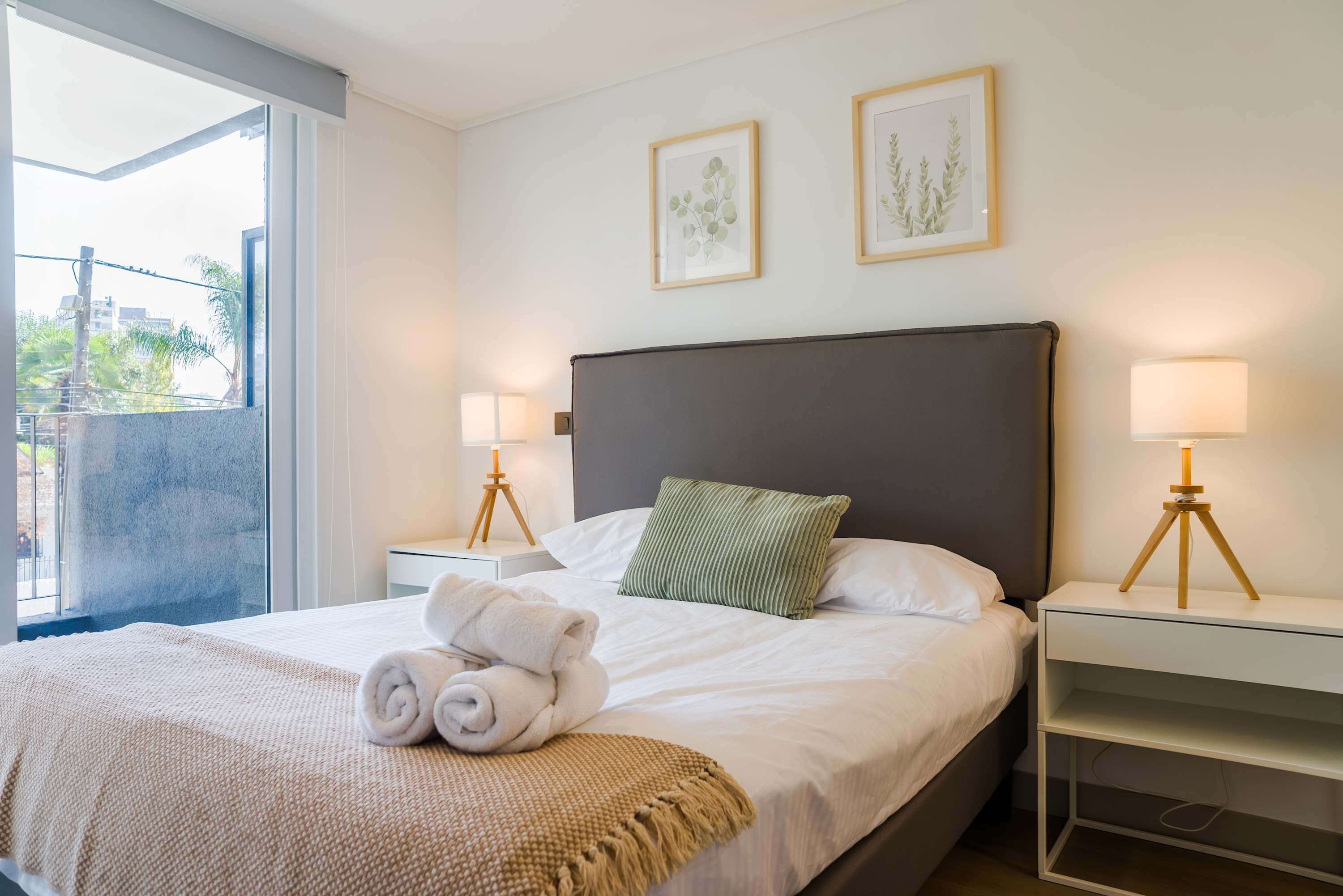 Relax in this serene bedroom with natural light and stylish decor, perfect for a restful stay.