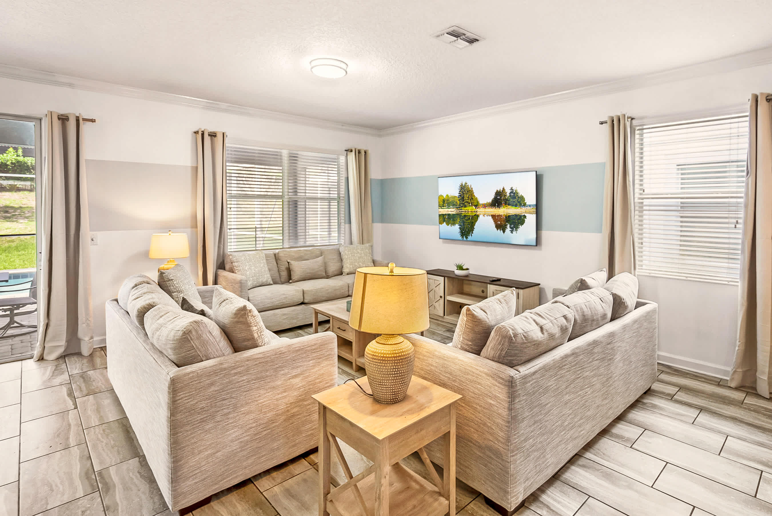 Relax in this spacious and cozy living room with ample seating and a large TV, perfect for family gatherings.