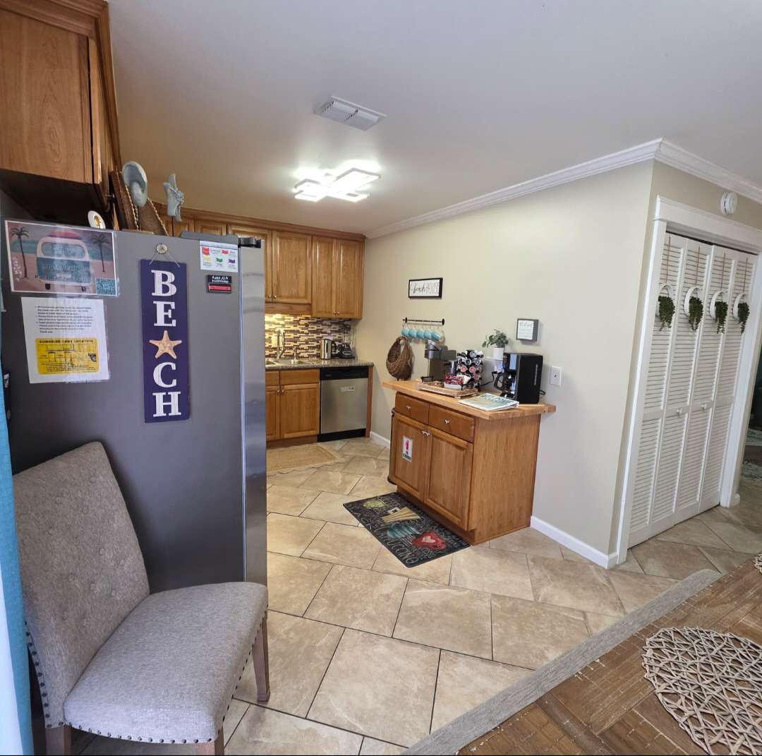 7405 Beach Dr A – Kitchen with wooden cabinets, tile flooring, stainless steel appliances, and a small seating area.