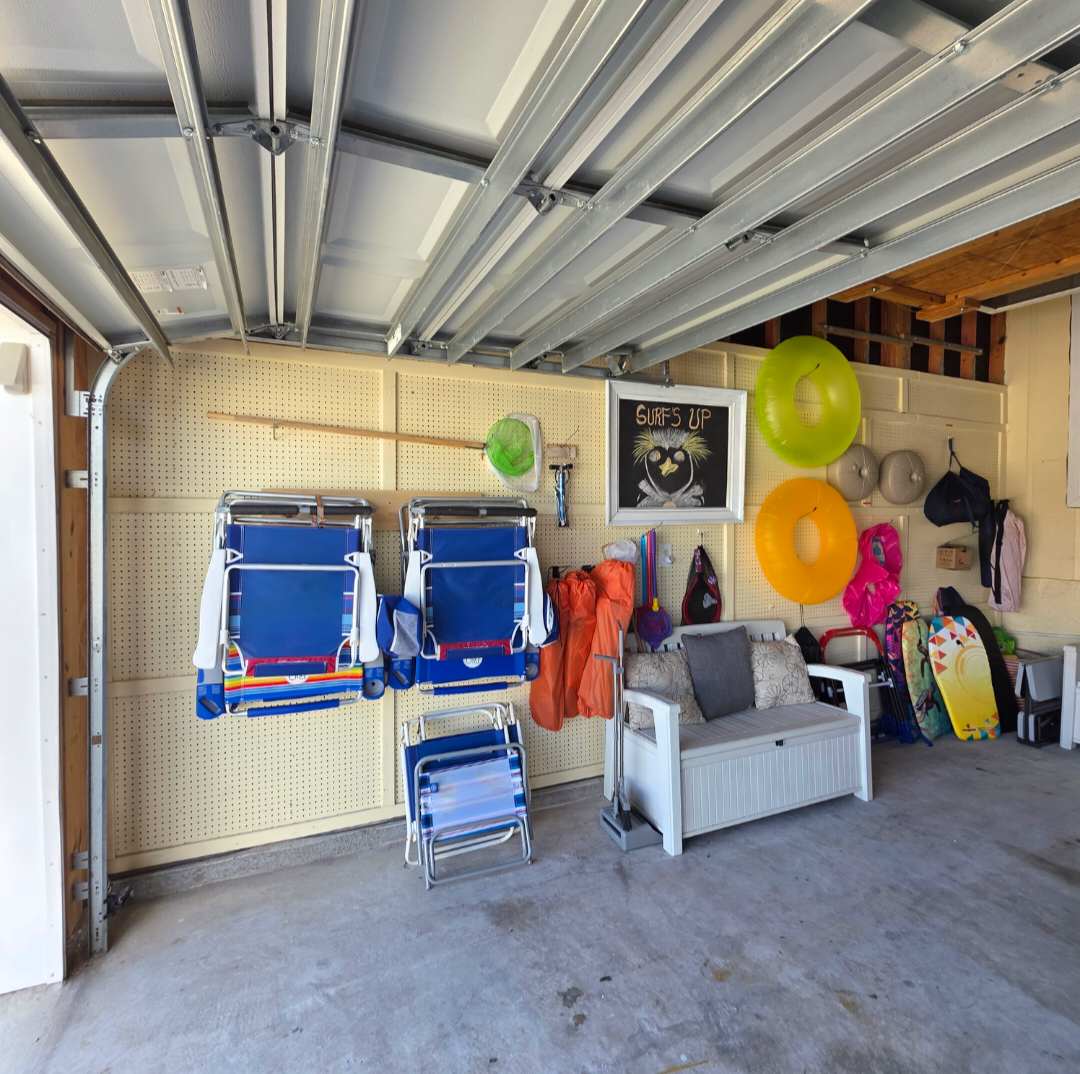 7405 Beach Dr A – Garage with beach chairs, colorful floaties, storage, and a seated area with cushions.