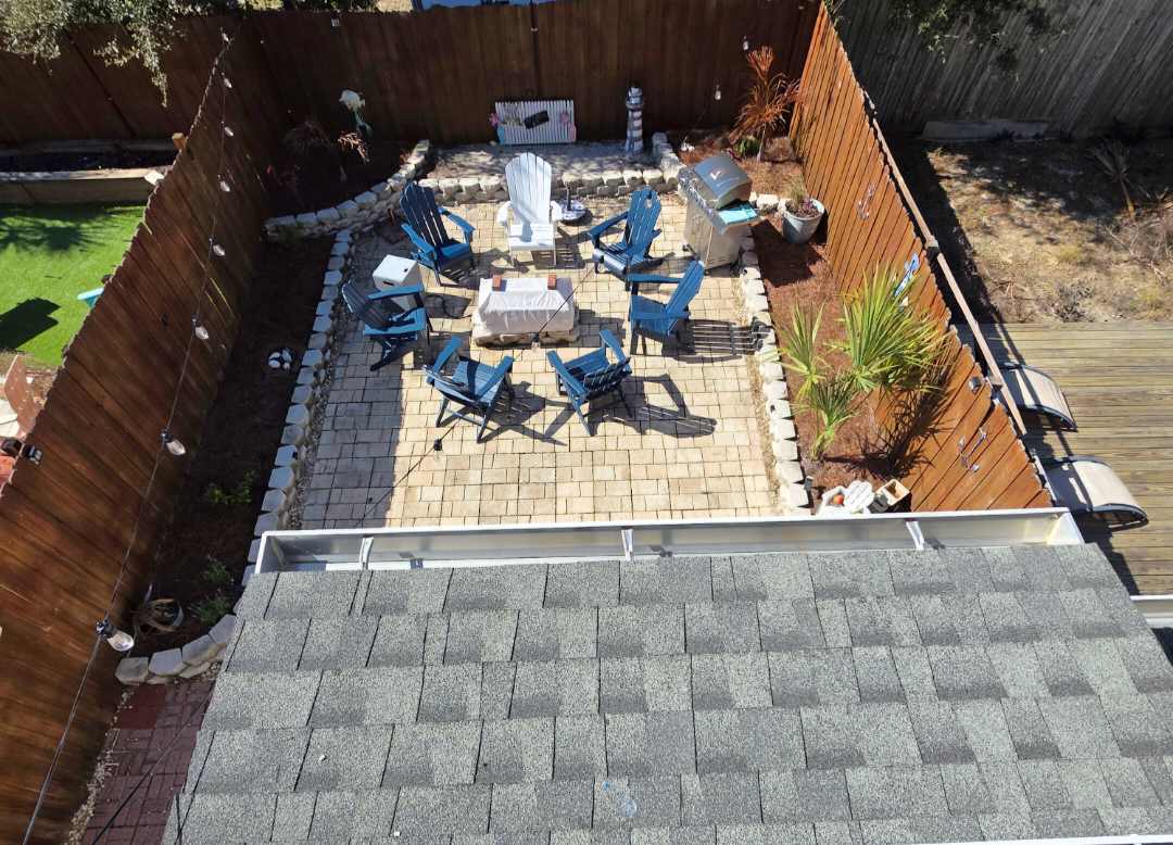 7405 Beach Dr A – Patio area with blue chairs, a table, grill, and landscaped garden.