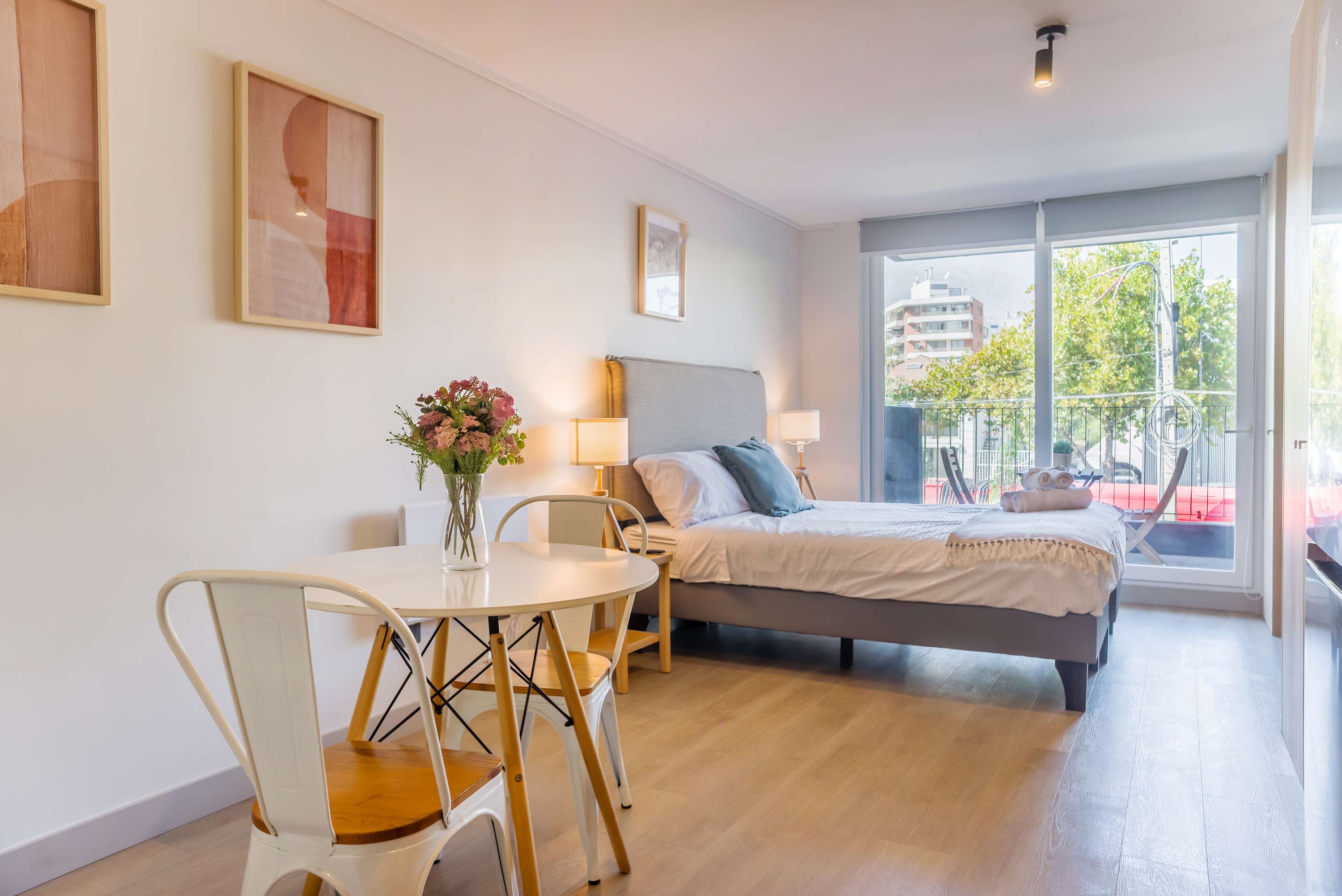 Bright and airy studio with a cozy bed, dining area, and large windows offering a lovely view.