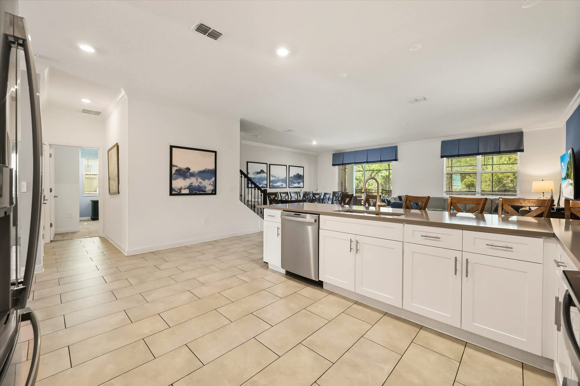 Spacious kitchen with a generous island, abundant seating, stainless-steel appliances, and leafy views through the windows—well suited to preparing meals and gathering with a large group.