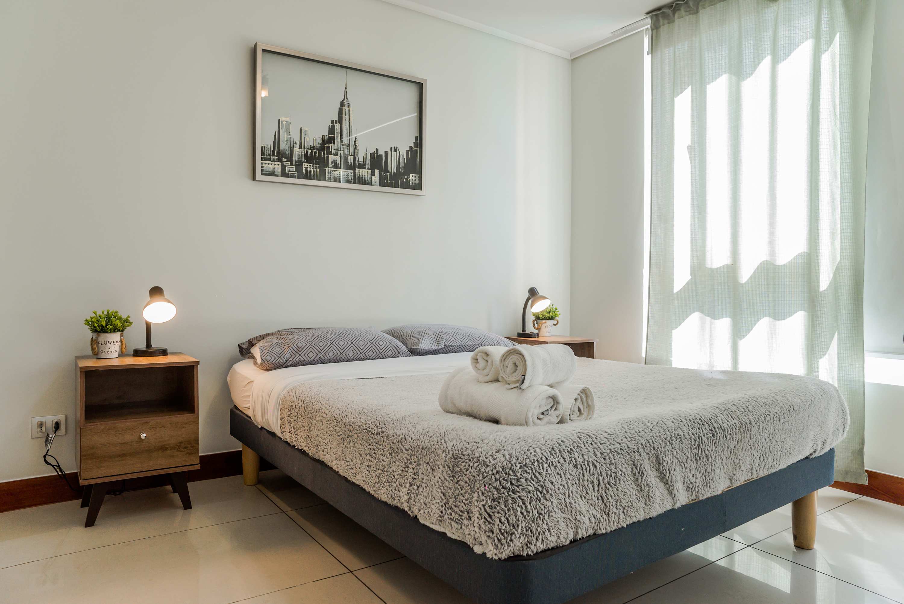 Relax in this cozy bedroom with plush bedding and plenty of natural light, perfect for a restful stay.