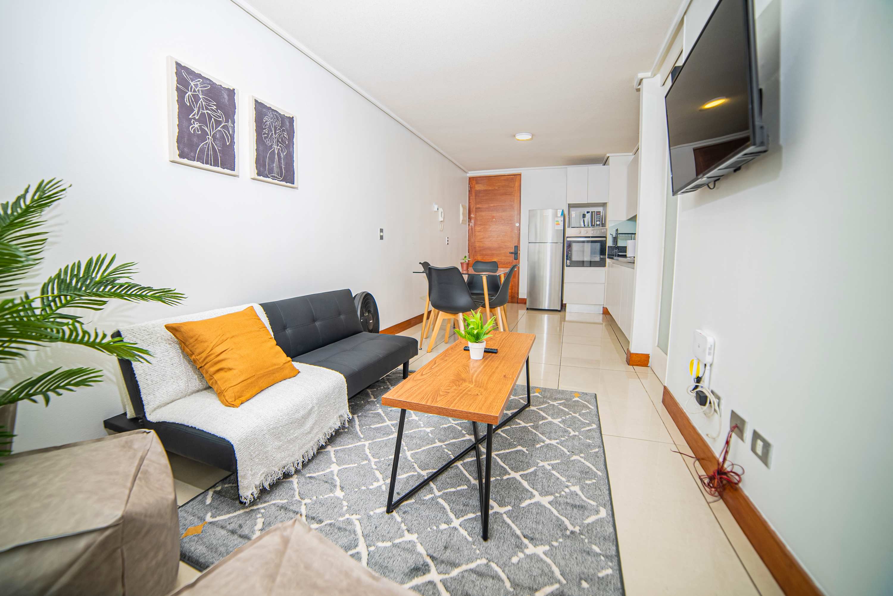 Cozy and modern living space with a stylish sofa, dining area, and smart TV, perfect for relaxation and entertainment.