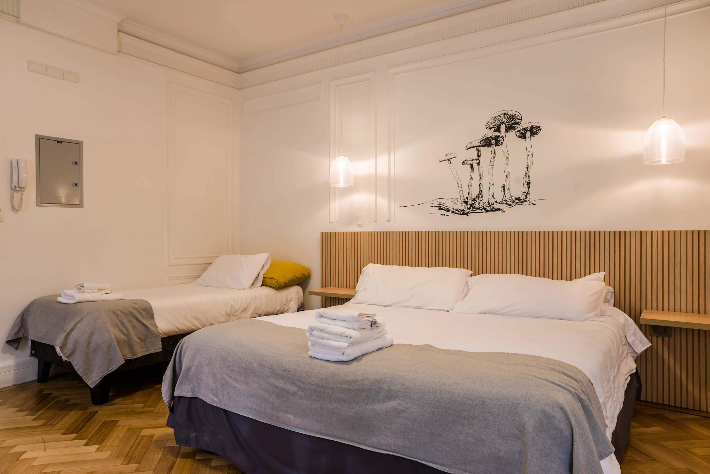 Relax in this stylish studio featuring a comfy double and single bed, unique wall art, and warm wooden accents.