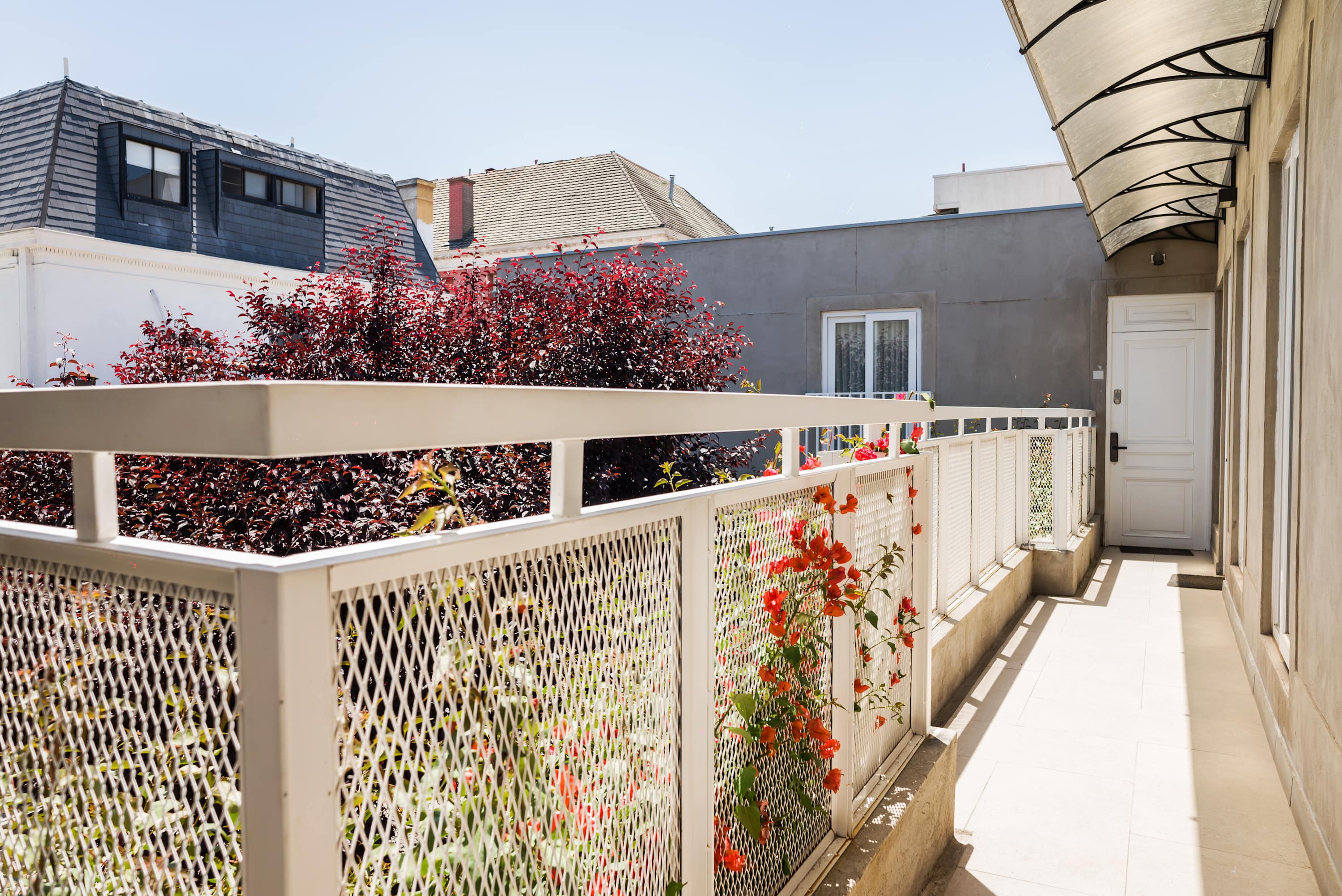 Enjoy a sunny escape on your private balcony, surrounded by vibrant flowers and charming rooftop views.