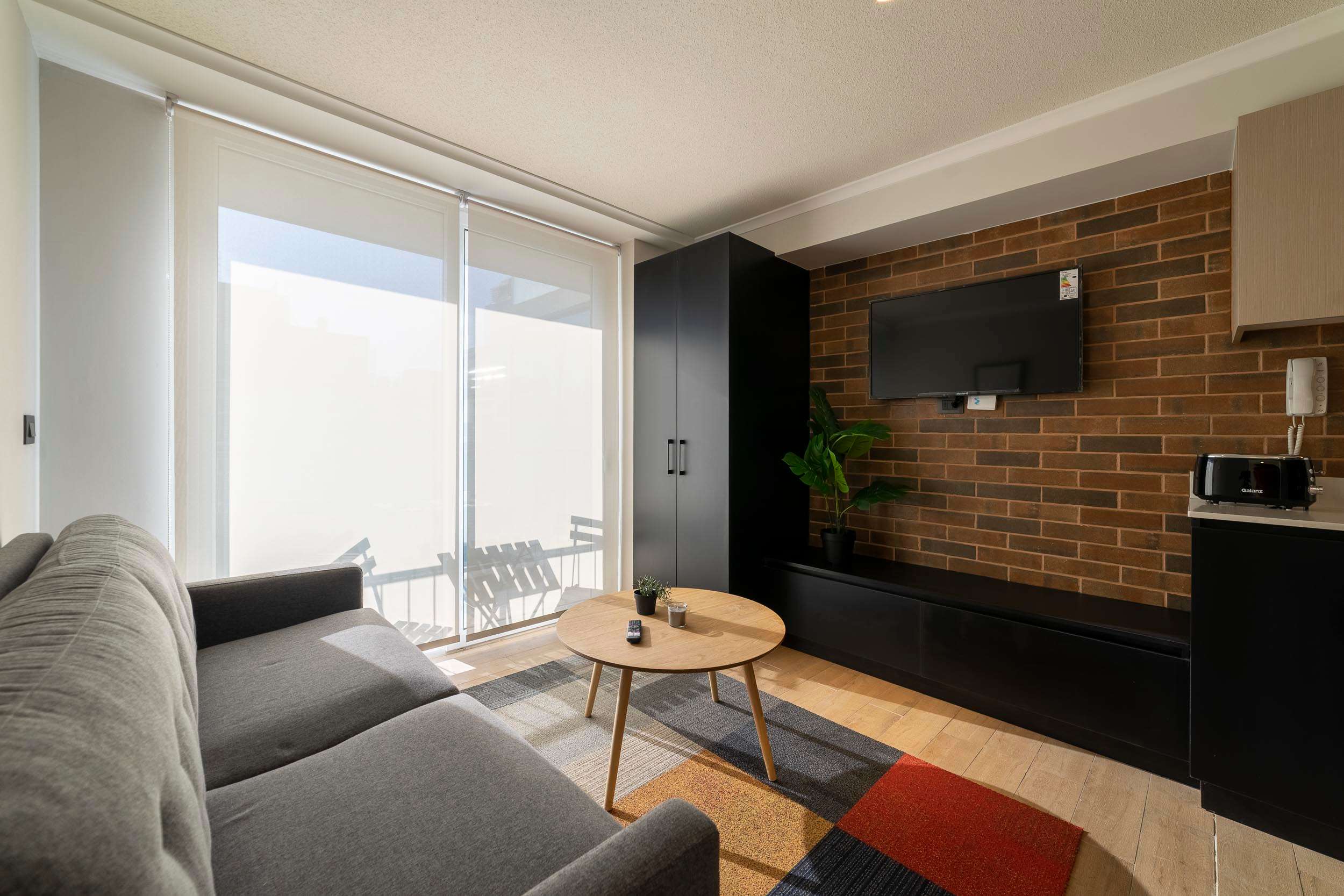 Relax in this stylish living area with a cozy sofa, flat-screen TV, and abundant natural light from the large window.