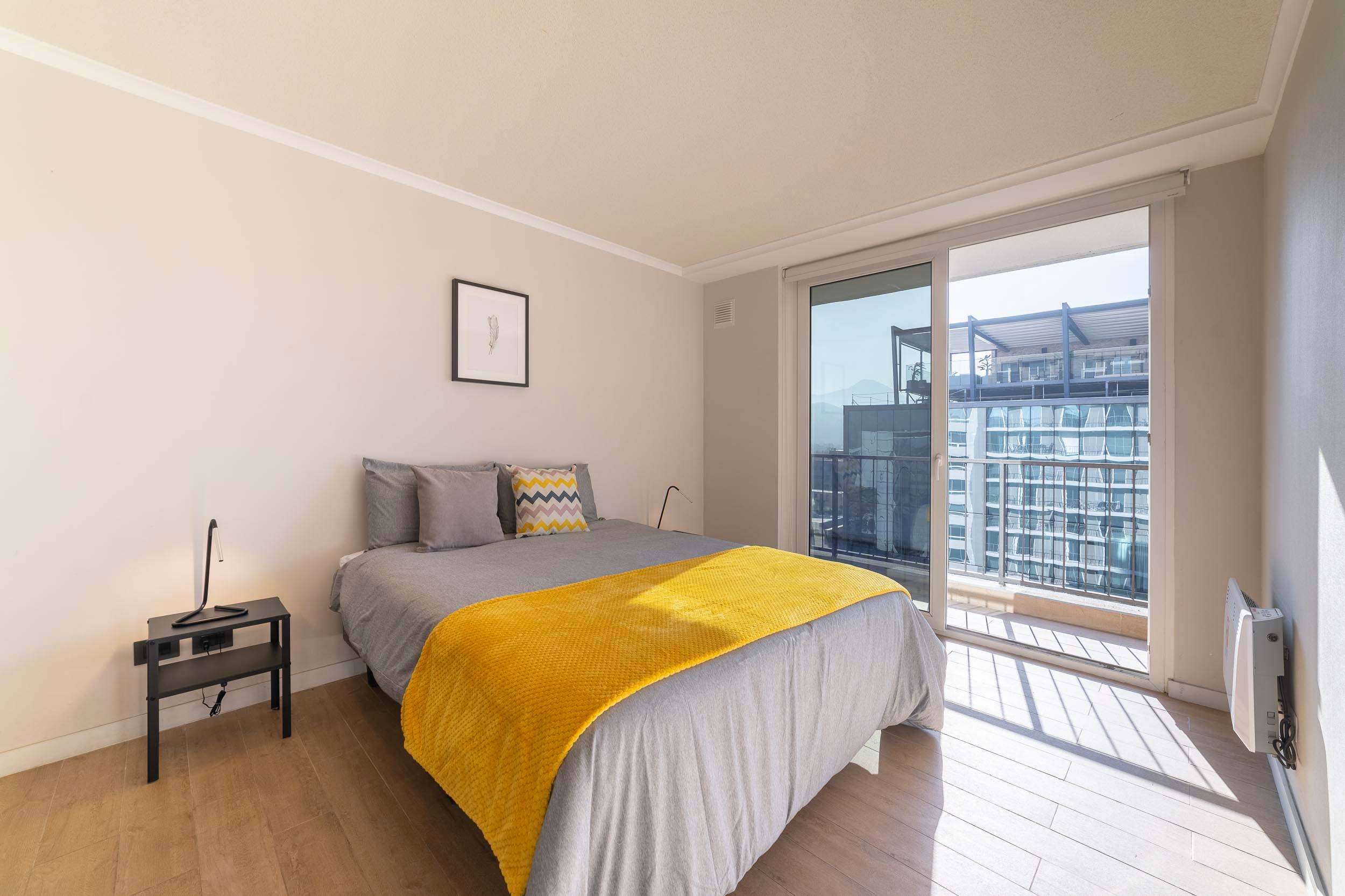 Bright and cozy bedroom with balcony access and city views, perfect for a relaxing stay.