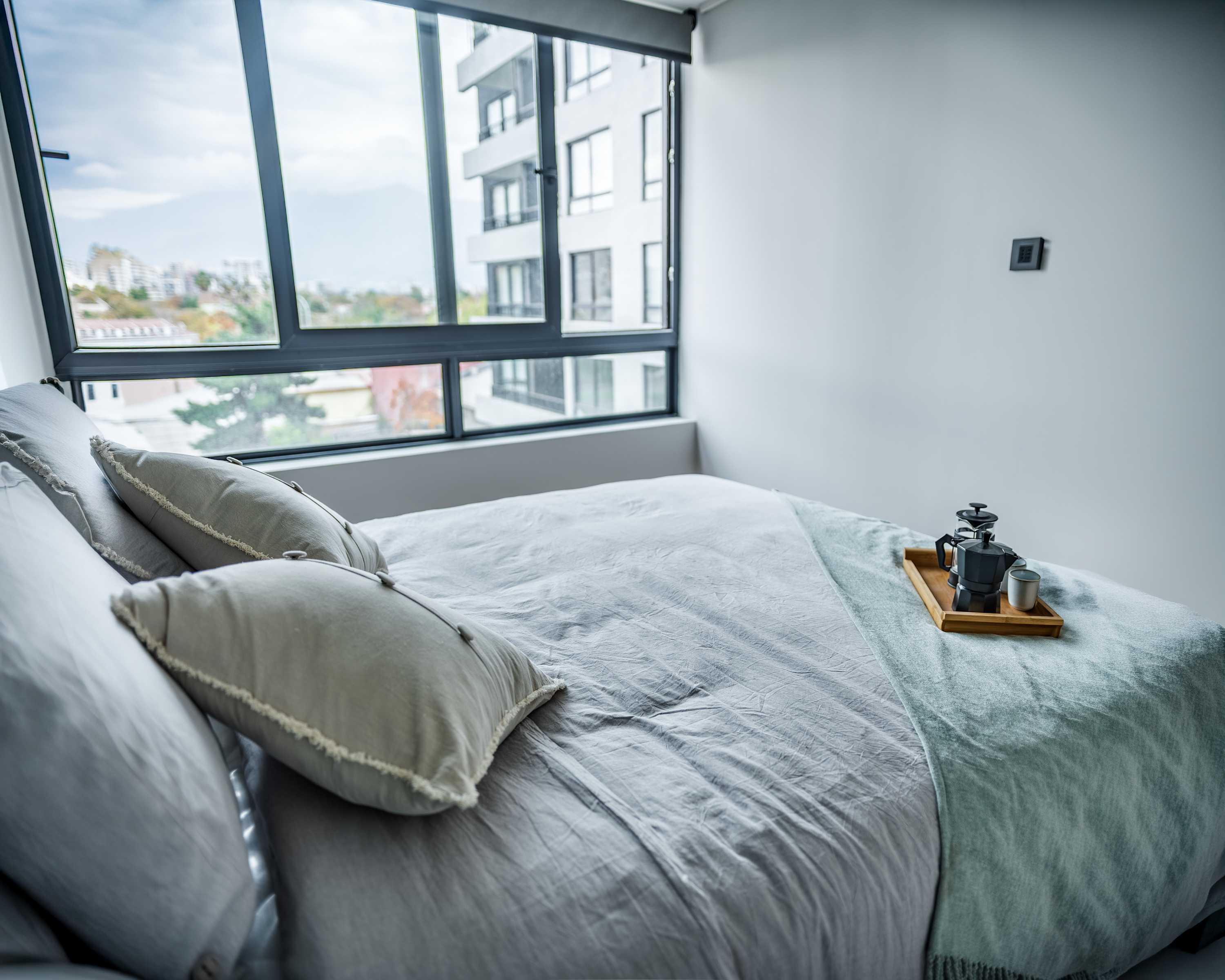 Relax in this bright and cozy bedroom with stunning city views and a welcoming coffee setup.