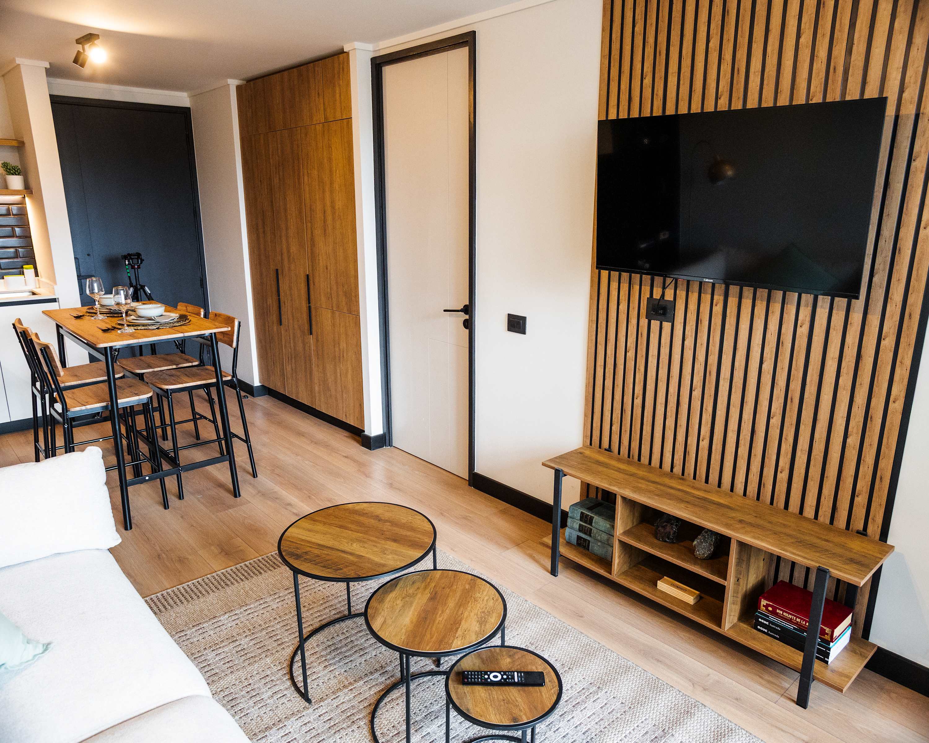 Cozy and modern living space with stylish wood accents and a mounted TV, perfect for relaxation and dining.