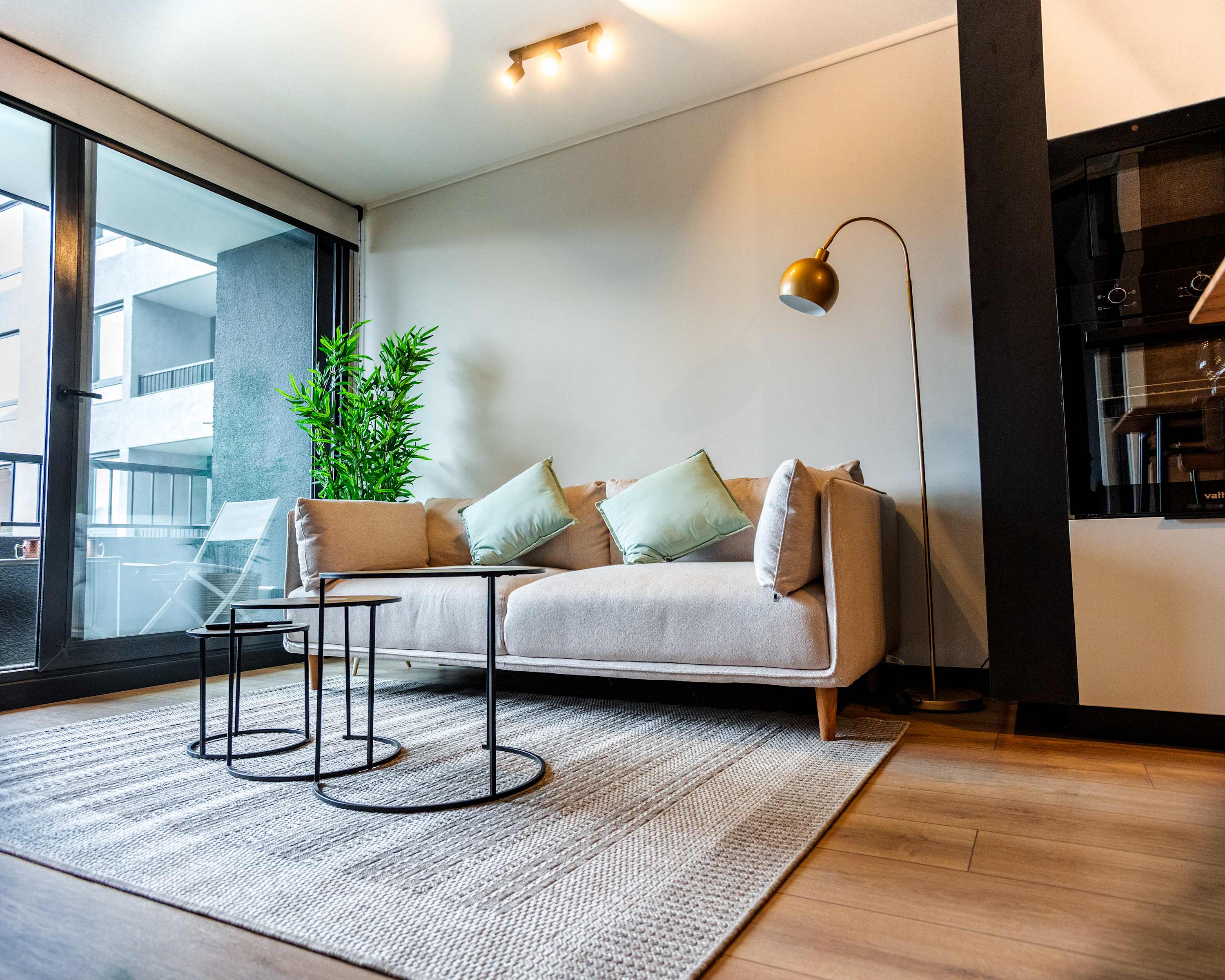 Relax in this stylish living room with a cozy sofa, chic decor, and abundant natural light from large windows.